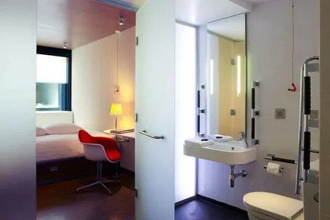 The ensuite bathroom of a citizenM London Bankside room, open to the bedroom through a glass and mirrored partition