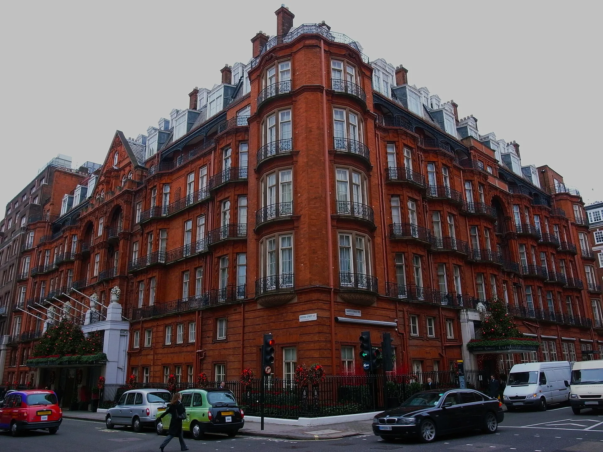 Claridge's red-brick and terracotta corner at Brook Street and Davies Street, with Christmas trees over the entrance canopies and taxis passing on the street below