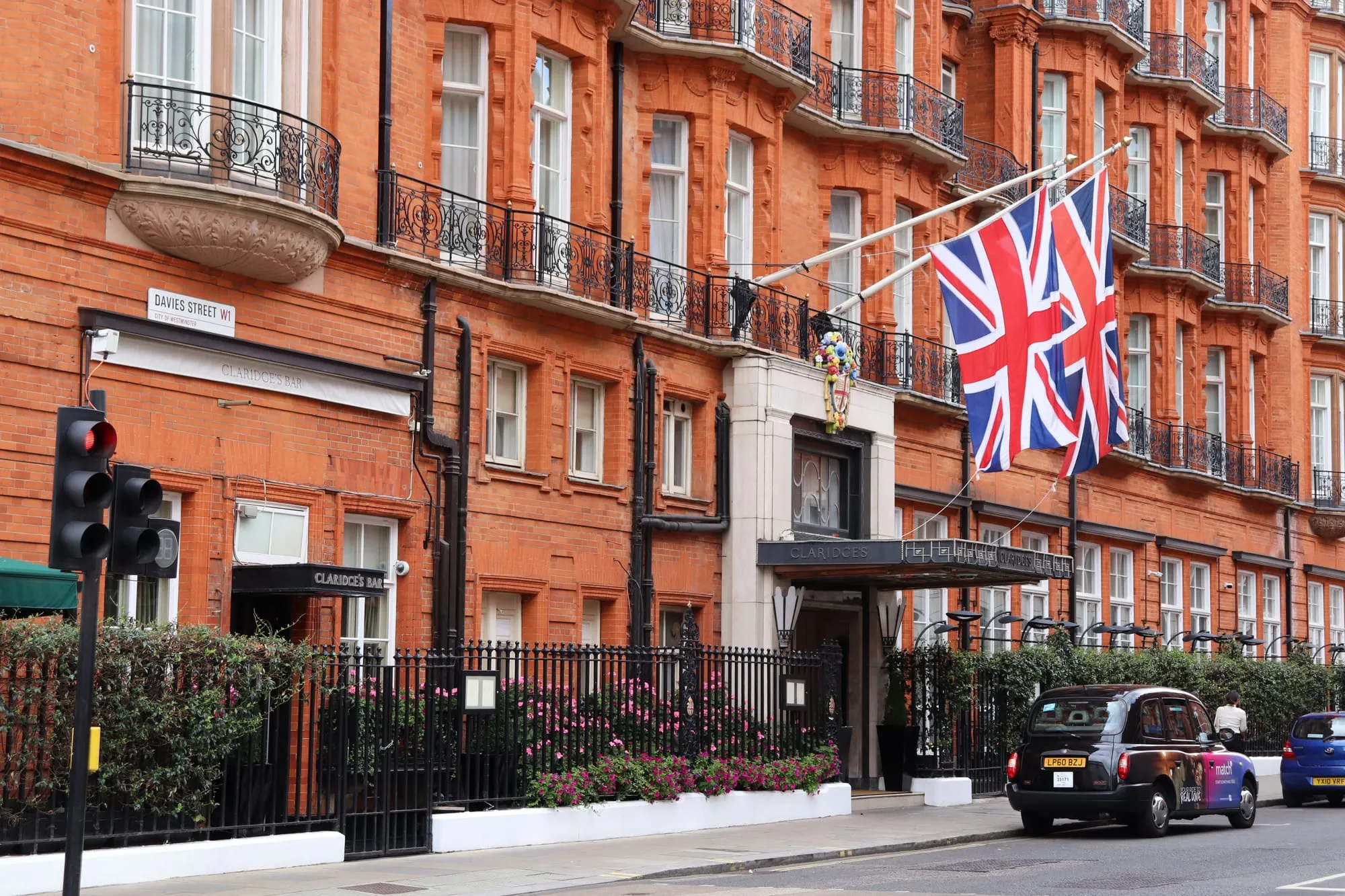 The red brick front of Claridge's on Davies Street in Mayfair, a Union Jack flying above the entrance and a black cab waiting at the kerb