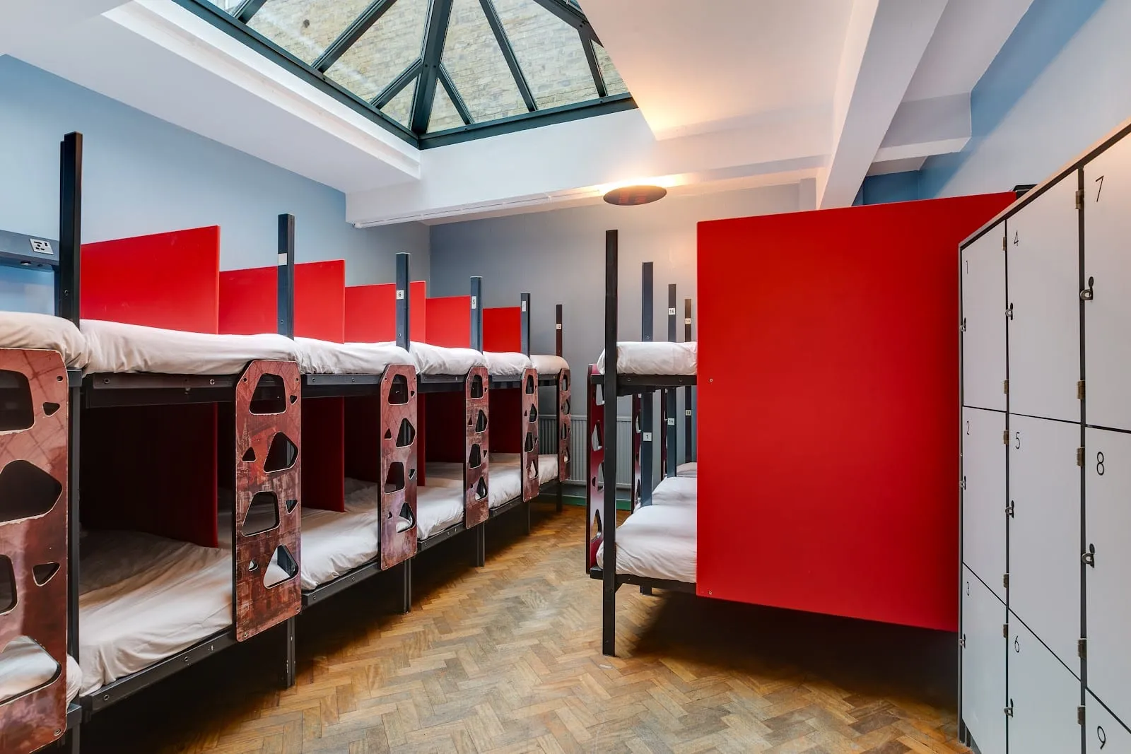 One of Clink 261's dorms, with red privacy screens between bunks and a skylight over the room