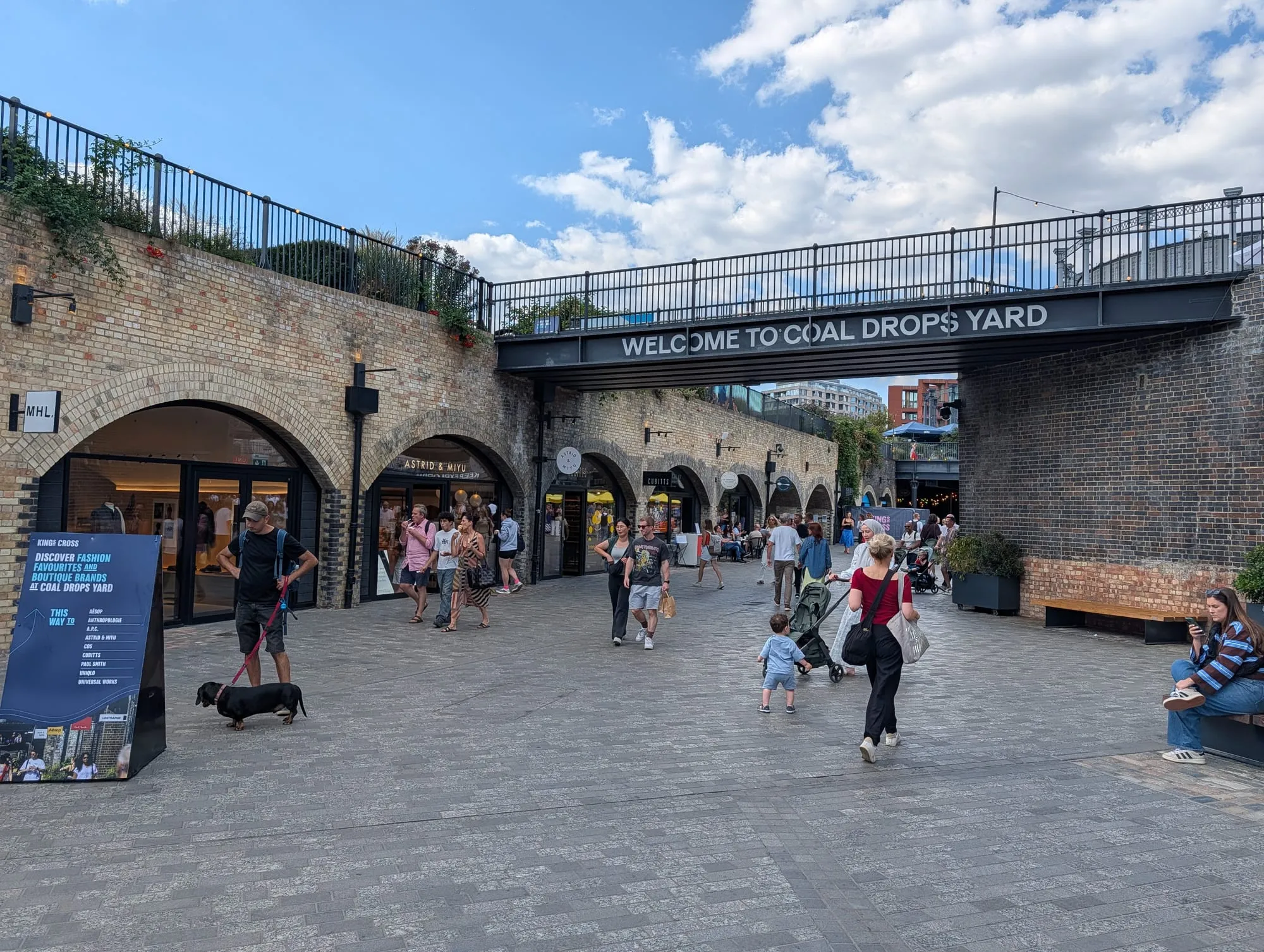 The entrance to Coal Drops Yard under a brick railway viaduct, lettered Welcome to Coal Drops Yard