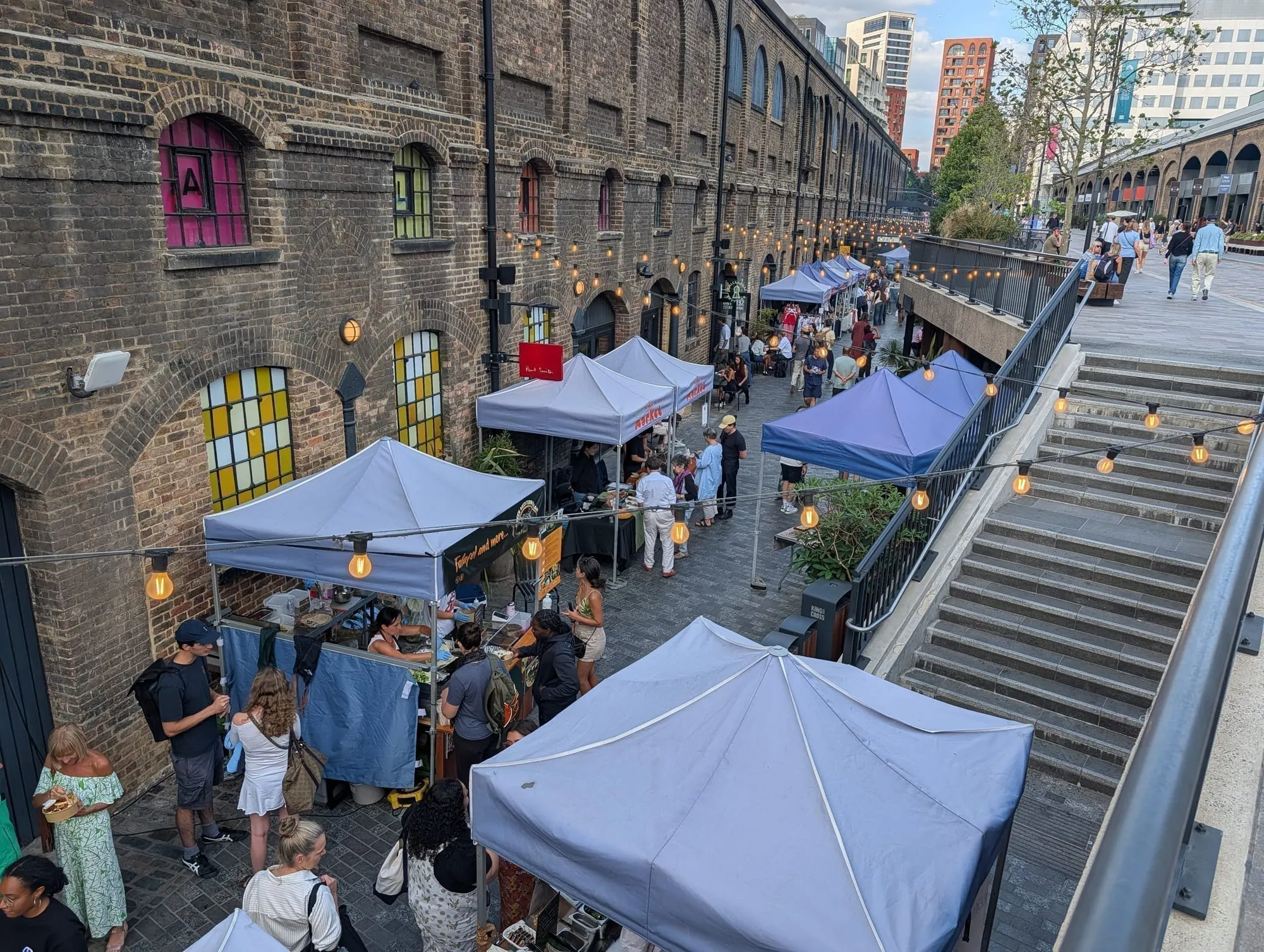 Market stalls with festoon lighting strung along the upper level of Coal Drops Yard