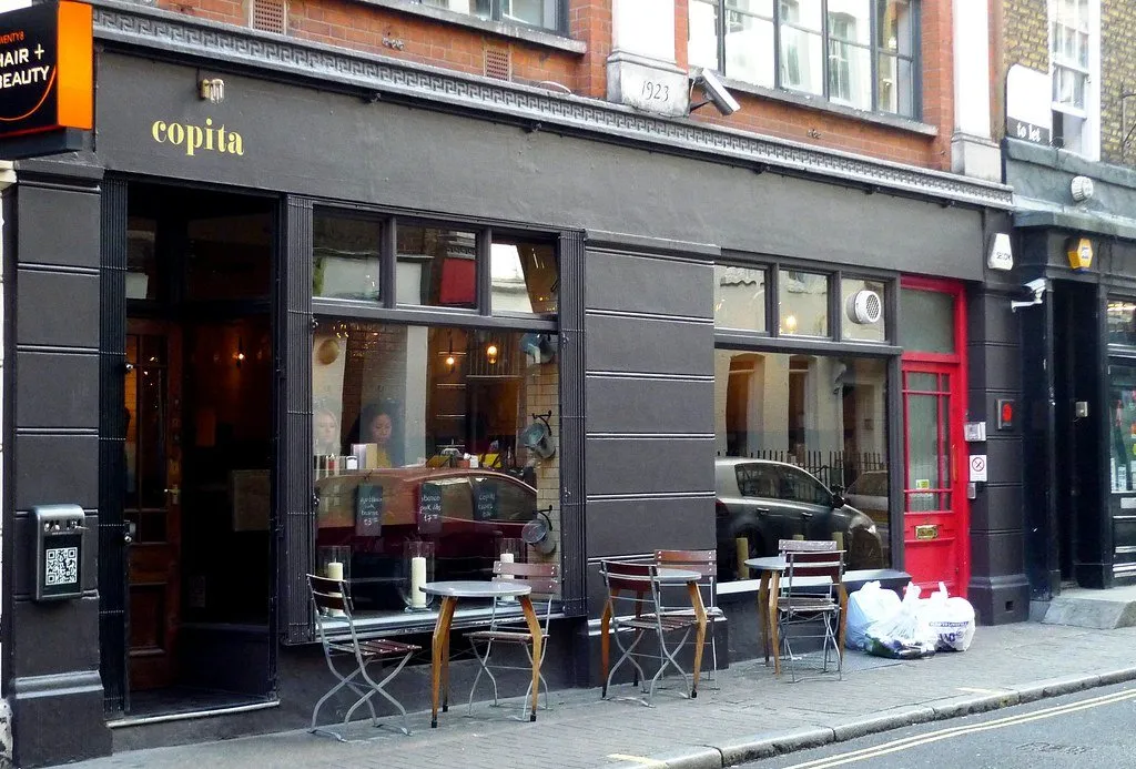The dark frontage and pavement tables of Copita on d'Arblay Street