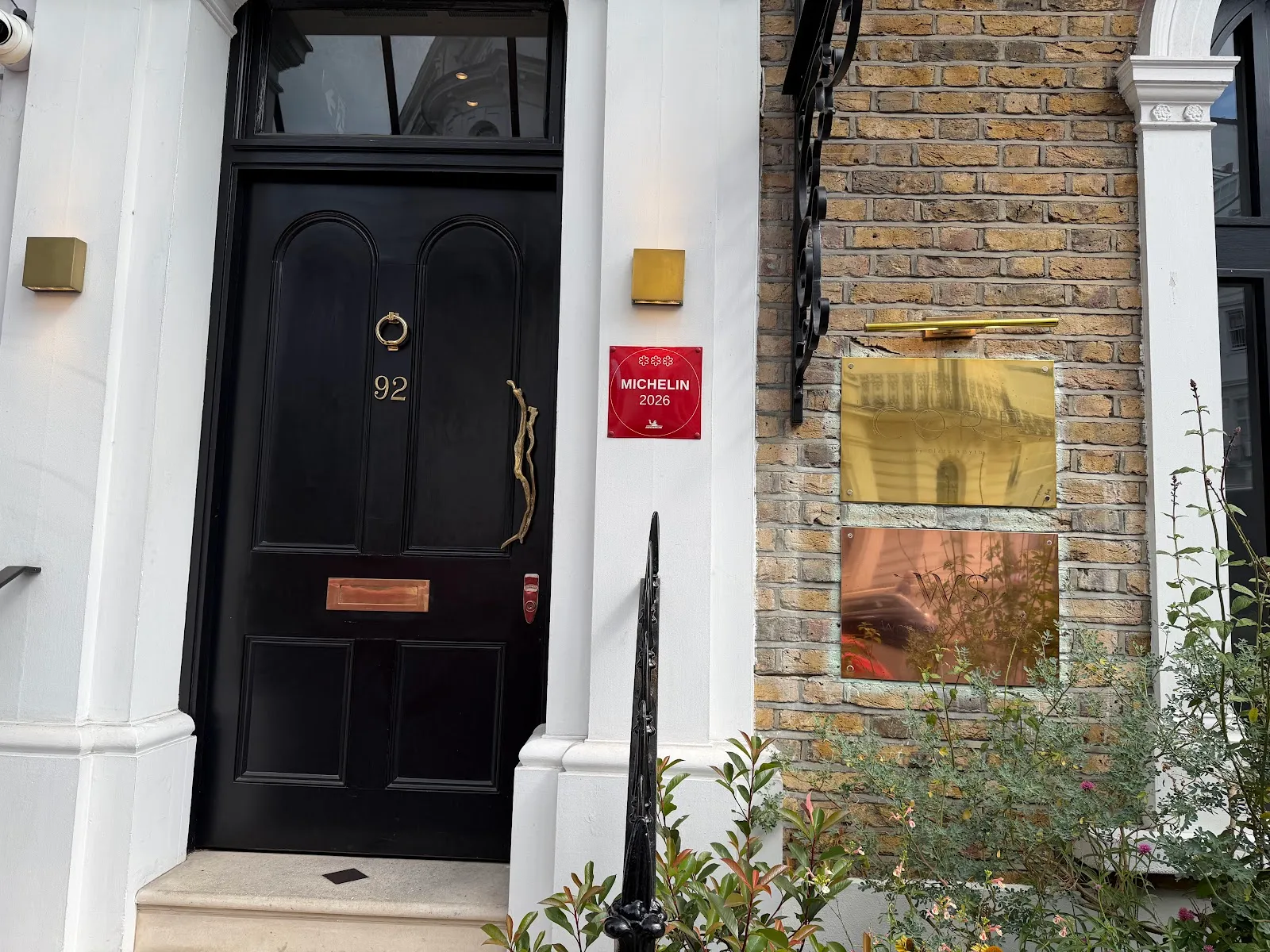 The black front door of Core by Clare Smyth at number 92, with a red Michelin 2026 plaque mounted beside it