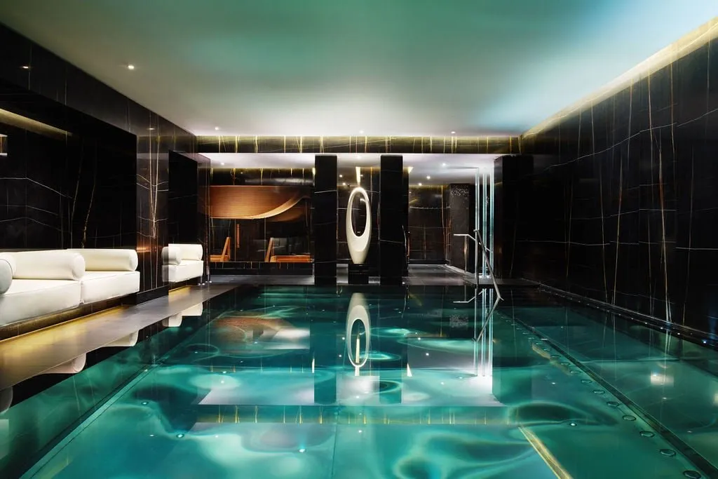 A pool in the spa at Corinthia London, lined with black marble and lit from below