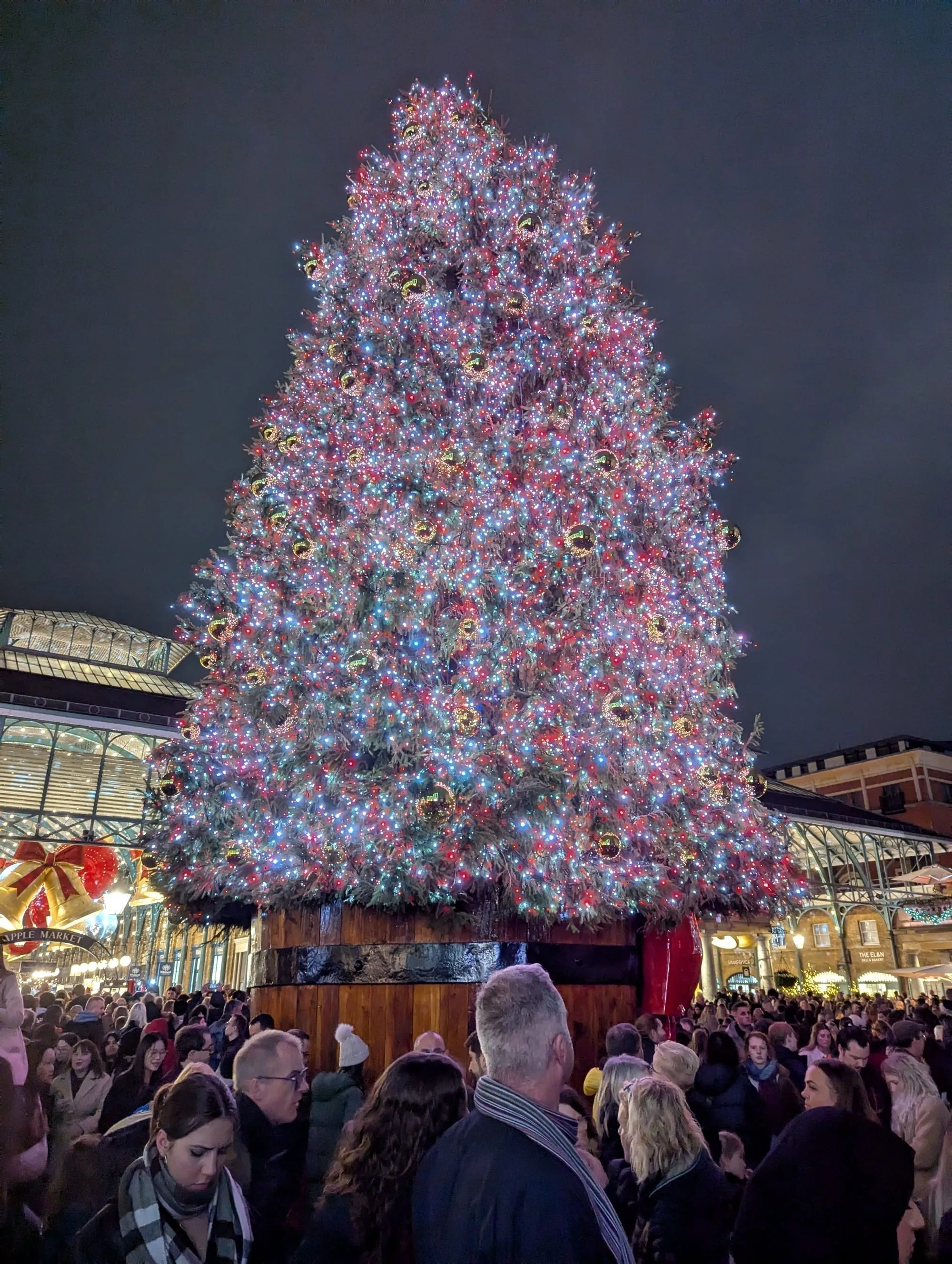 Covent Garden's illuminated Christmas tree at night in the Piazza, decorated with white and red lights