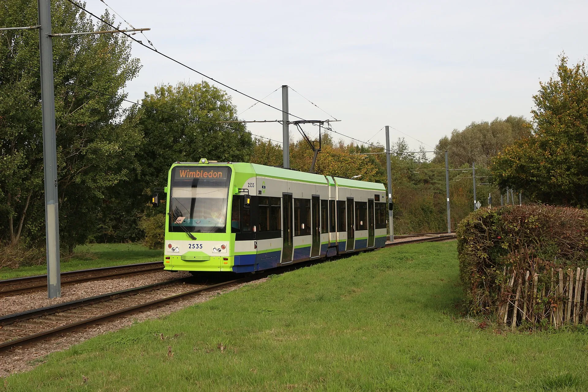 A green, white and blue London tram travelling through the Croydon area.