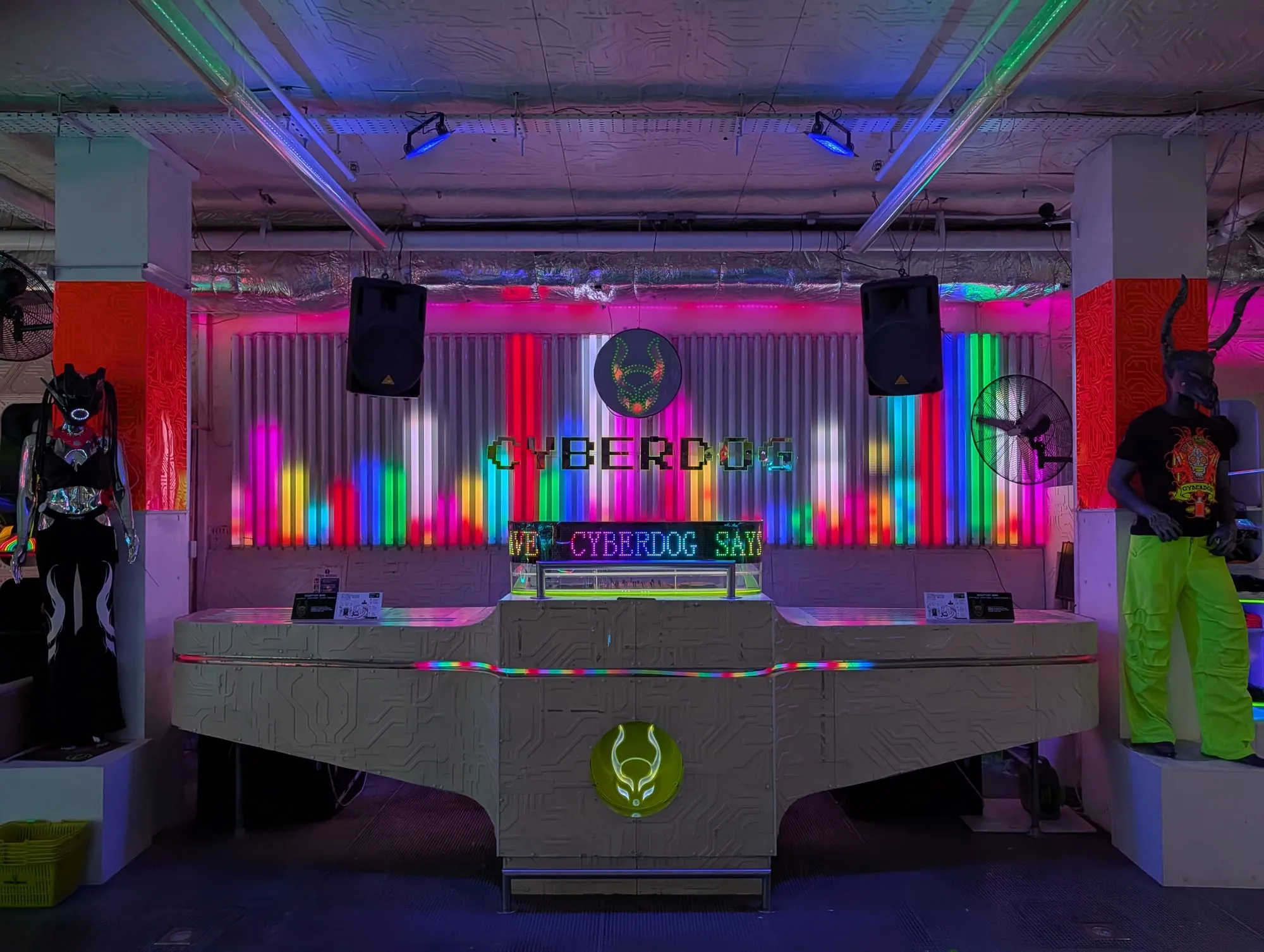 The neon-lit interior of Cyberdog in Camden, with a DJ booth and a sign reading Raving Since '94