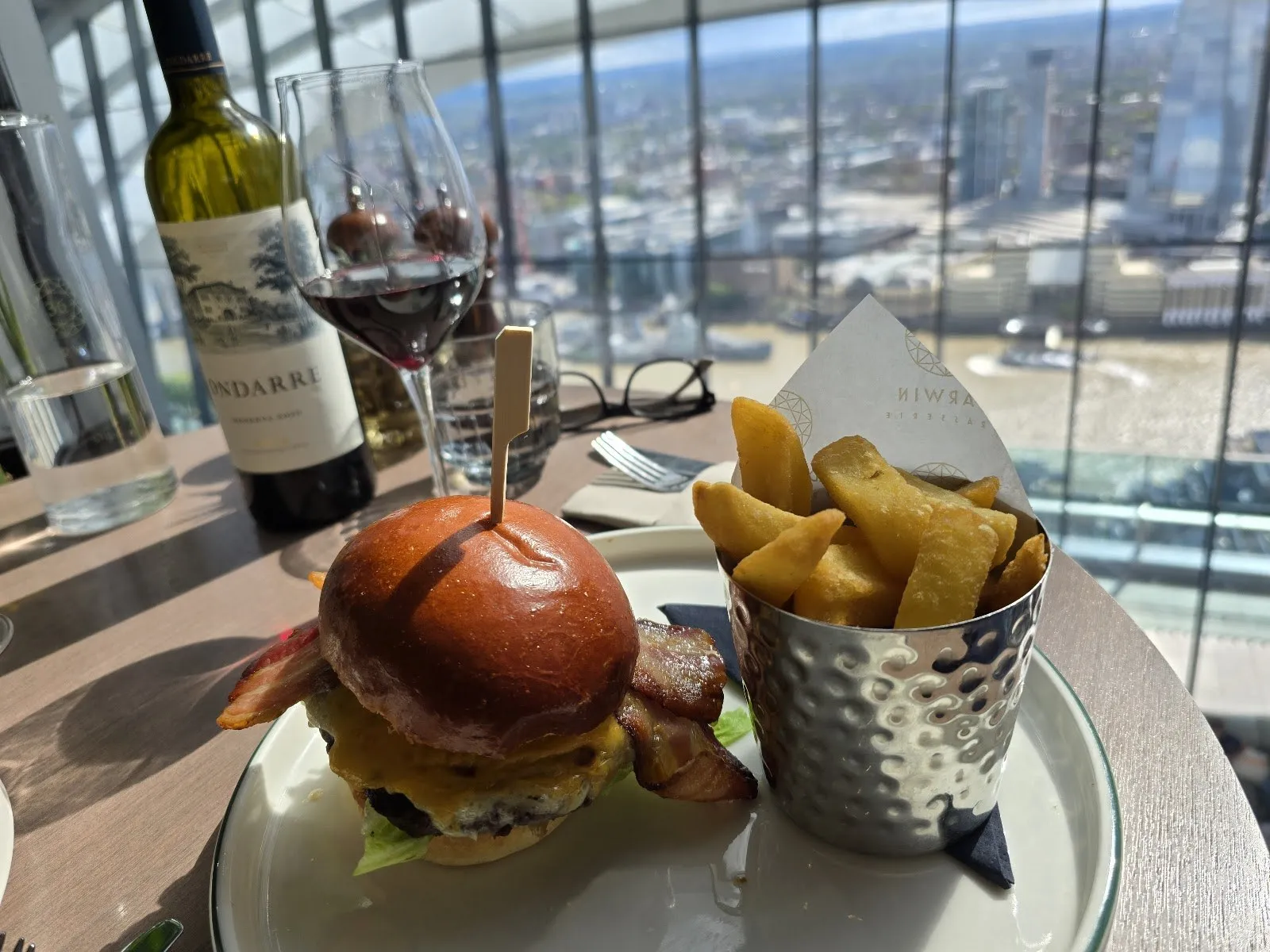 A burger with bacon and chips at a window table, the Thames and the South Bank far below
