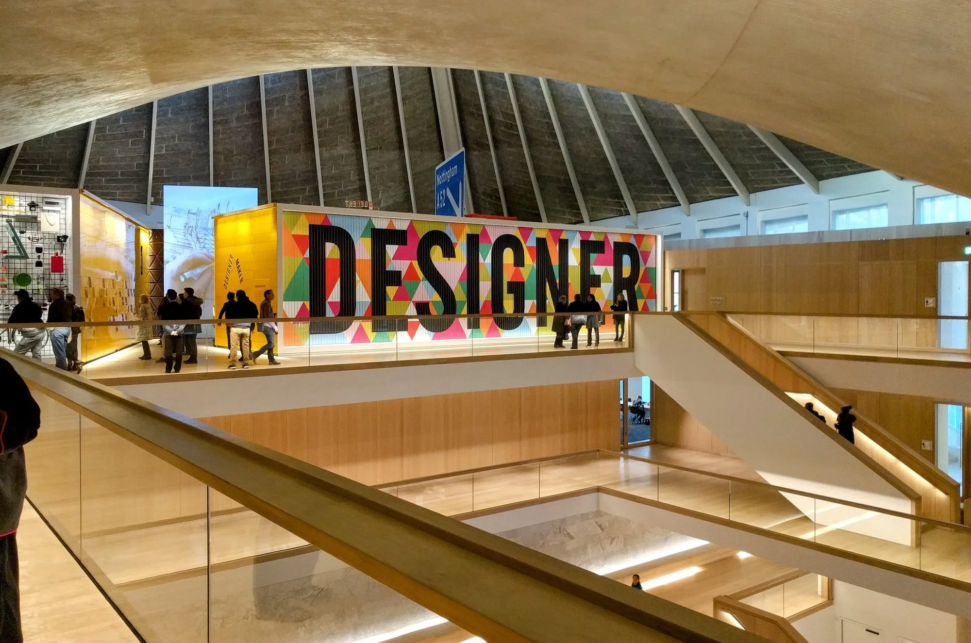 The oak-lined atrium of the Design Museum, looking up to the free top-floor gallery beneath the swooping concrete roof of the former Commonwealth Institute