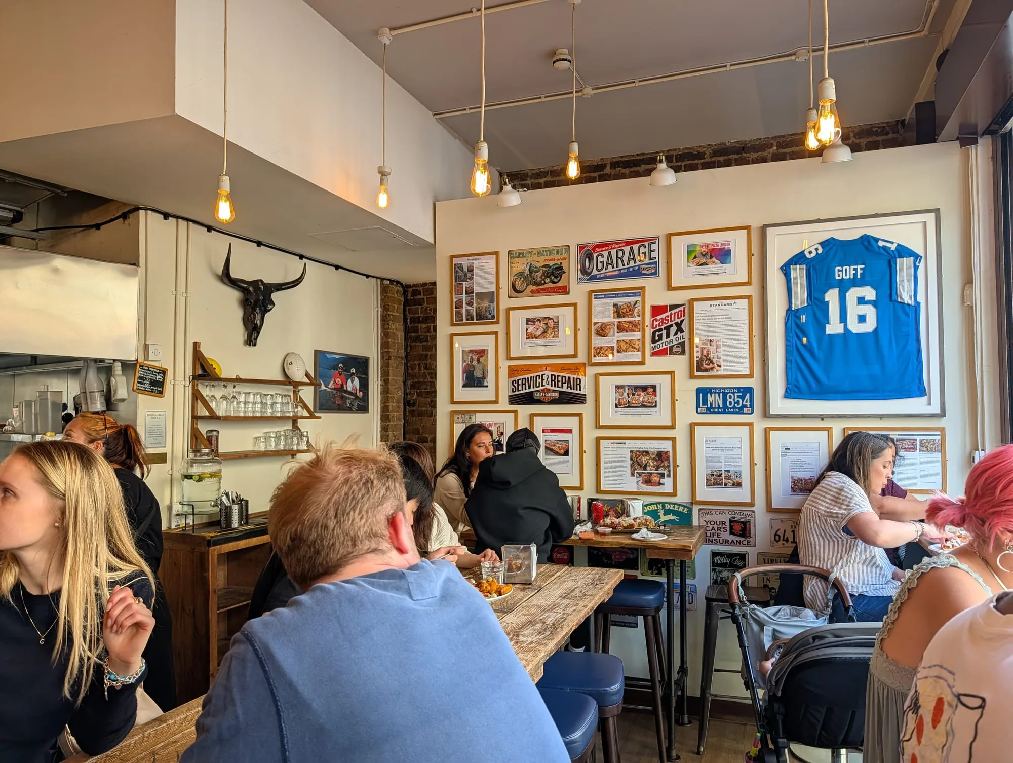 The dining room at Detroit Pizza London, brick walls hung with framed American memorabilia above a long shared table