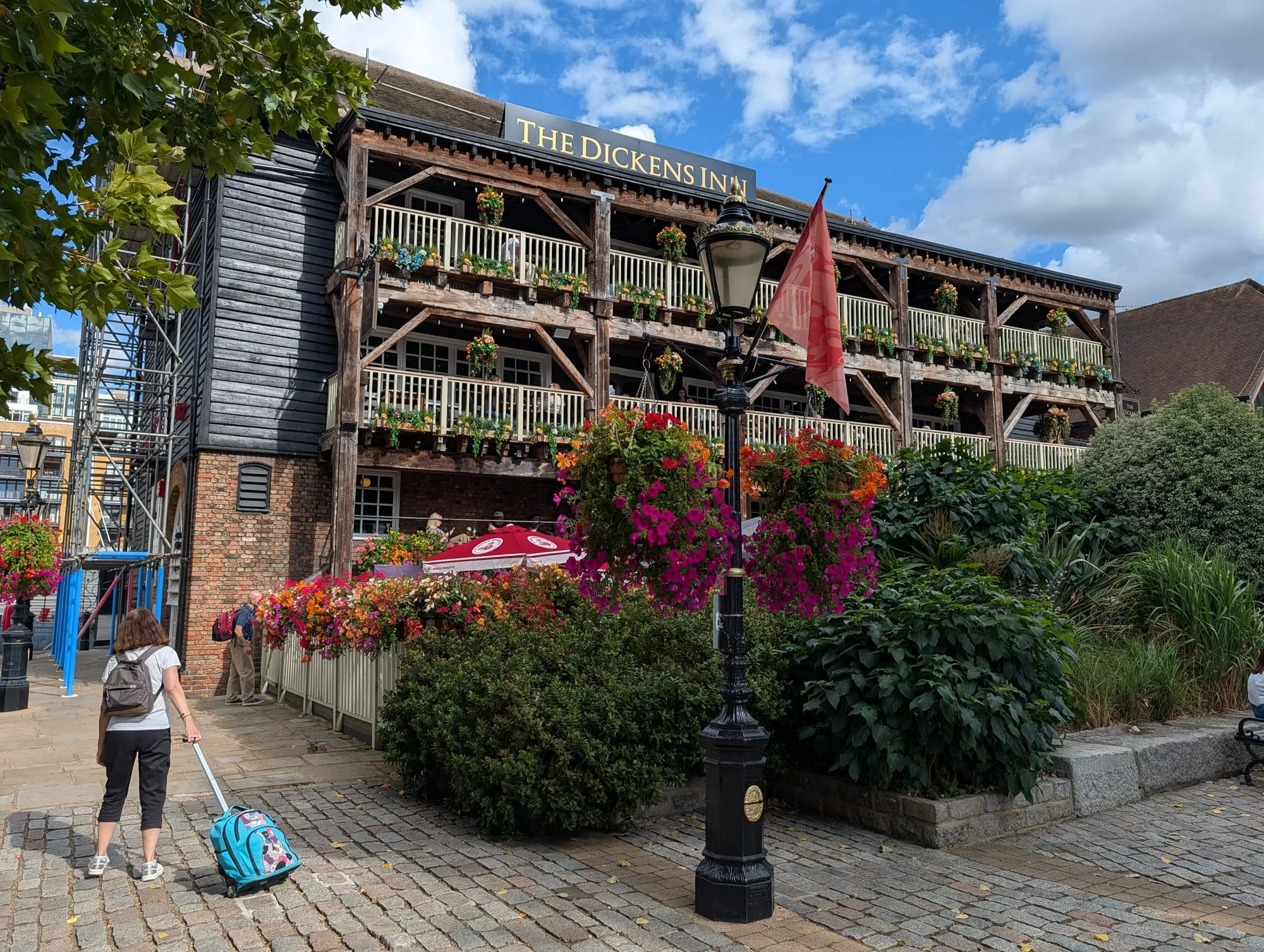 The Dickens Inn at St Katharine Docks, a timber-framed warehouse with three tiers of balconies covered in hanging baskets of flowers