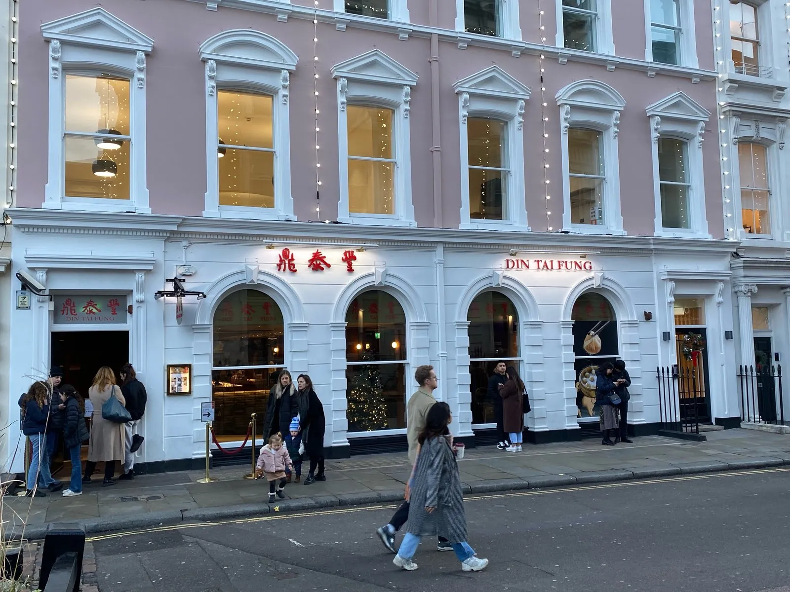 The white frontage of Din Tai Fung in Covent Garden with people queueing