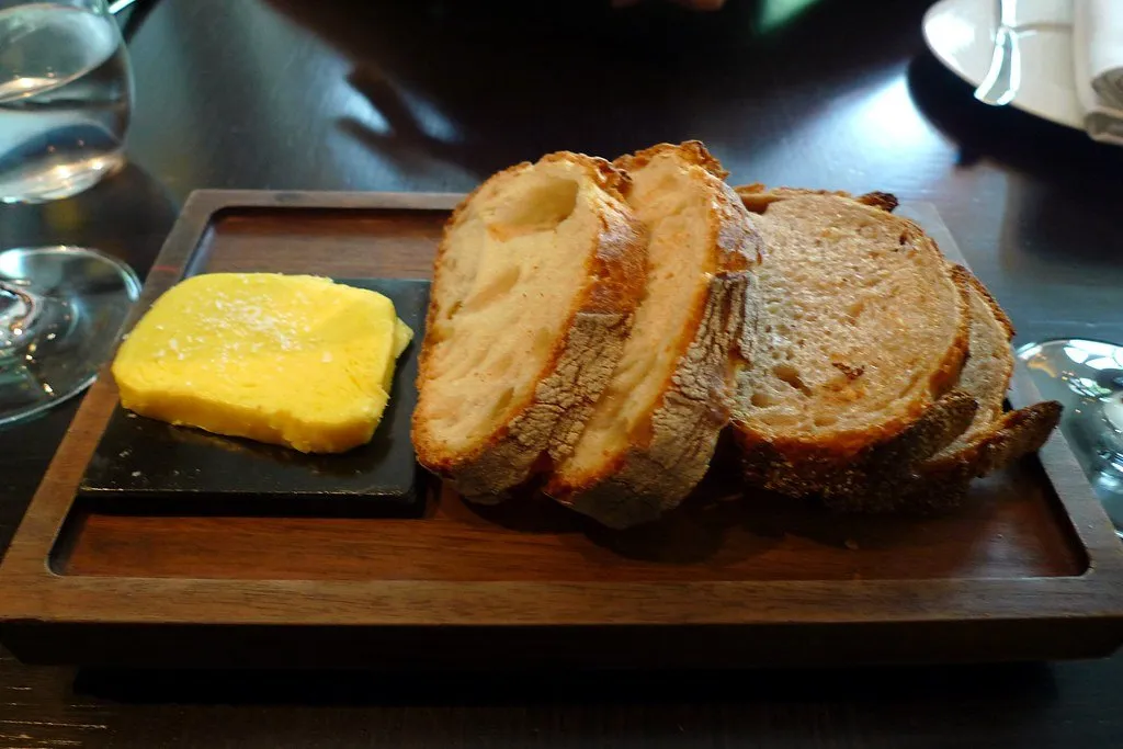 Sliced bread with a slab of butter on a black board