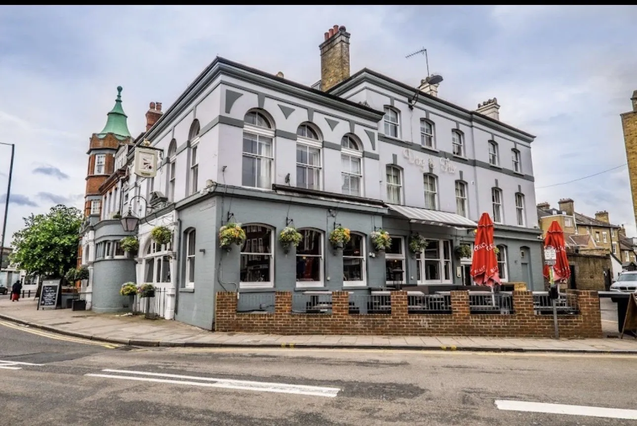 The Dog & Fox pub on Wimbledon High Street, a corner building with a turret next door and hanging baskets over the ground-floor windows