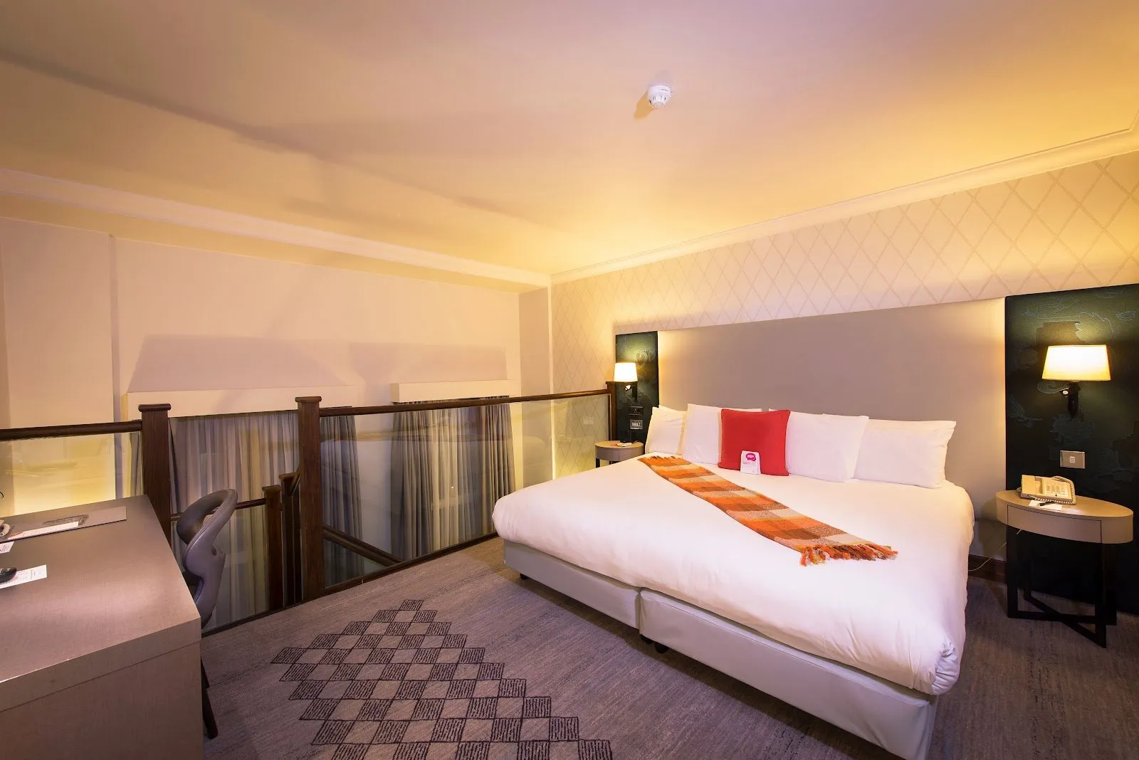 A split-level hotel room at DoubleTree by Hilton London Kensington showing a lower double bed and railed mezzanine level