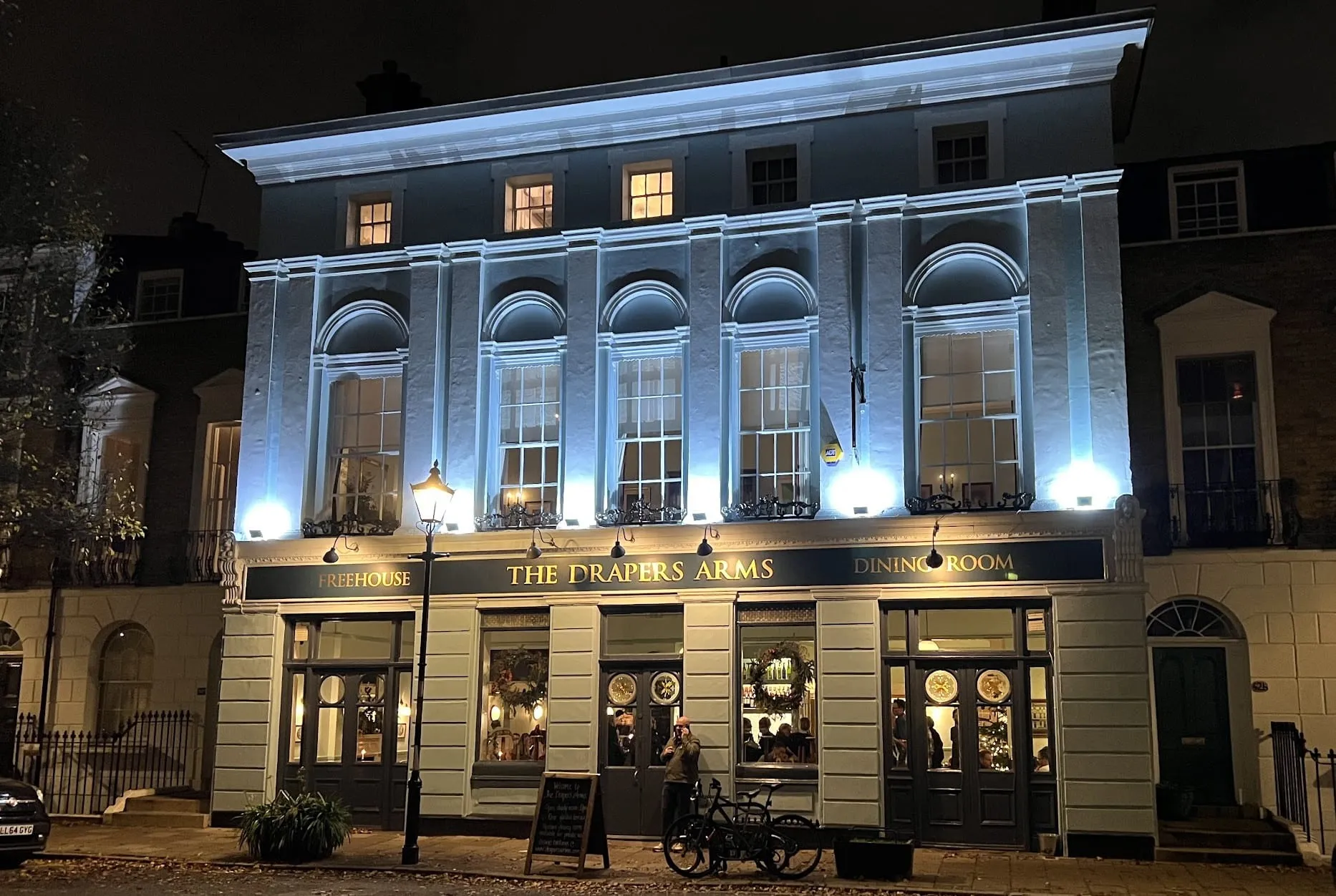 The Drapers Arms on a Barnsbury street at night, its Freehouse and Dining Room signs lit above the windows