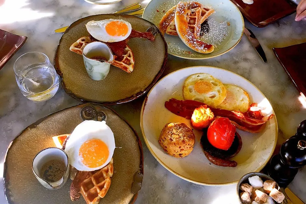 Brunch plates at Duck & Waffle: waffles with duck egg, a full breakfast with bacon and tomato, and pancakes