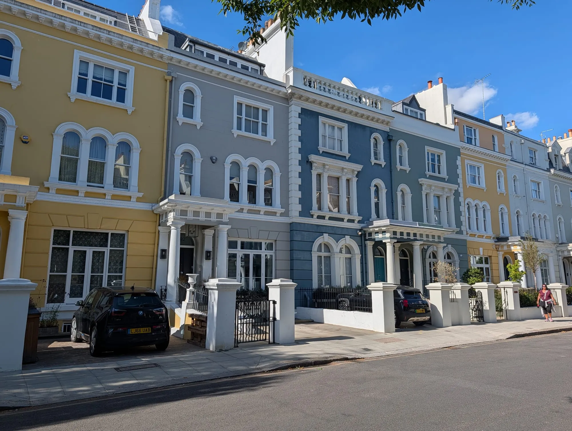 A curved terrace of stucco houses on Elgin Crescent painted butter yellow, powder blue and white