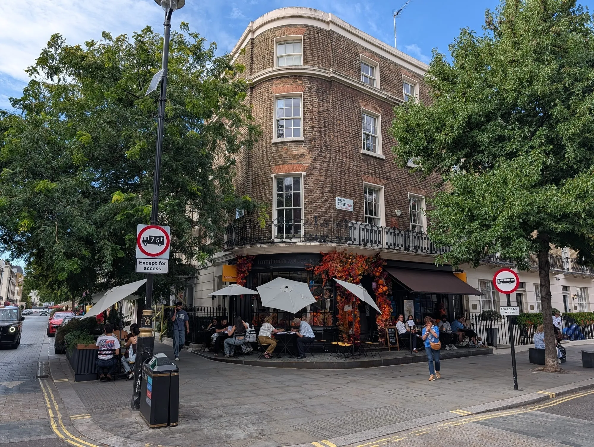 A corner restaurant on Elizabeth Street with an awning and pavement tables under autumn foliage