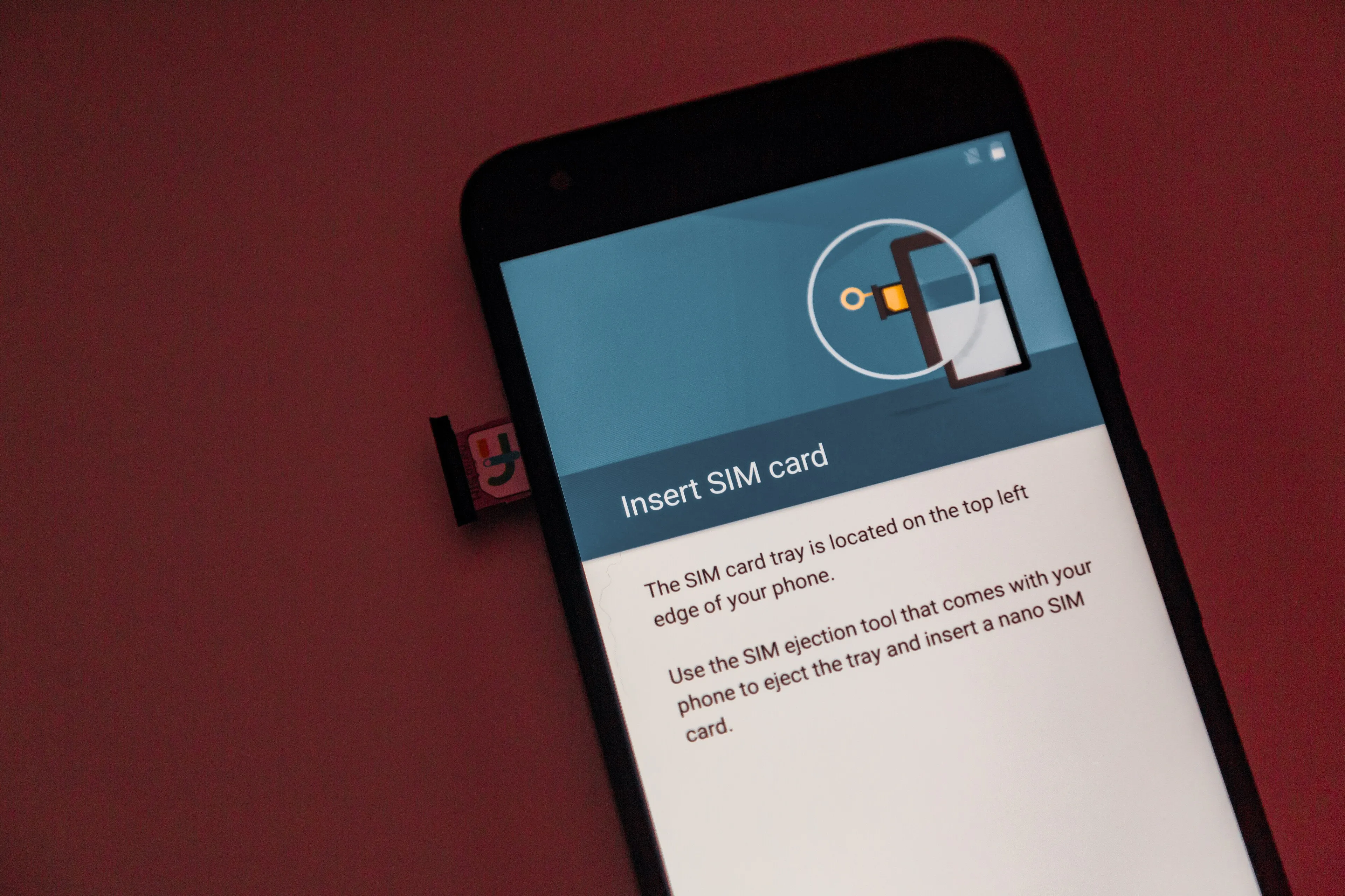 A smartphone displaying SIM card insertion instructions beside a physical SIM