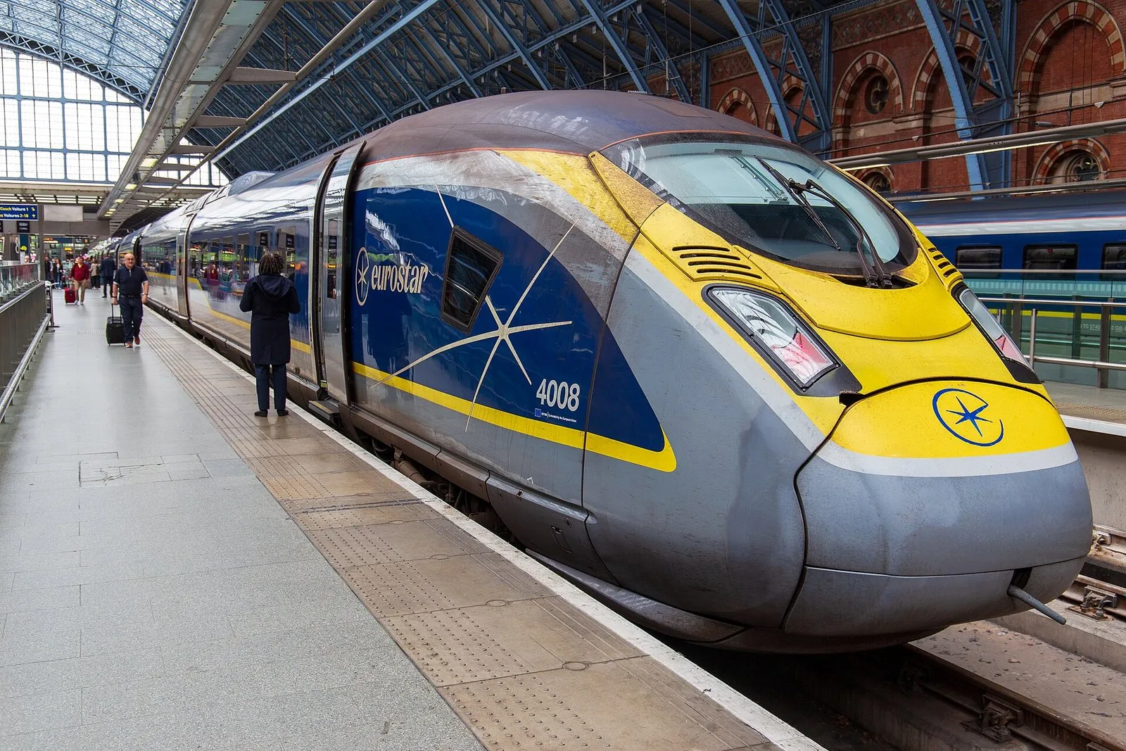 A blue and yellow Eurostar e320 at a platform of St Pancras International, under the station's arched iron-and-glass roof