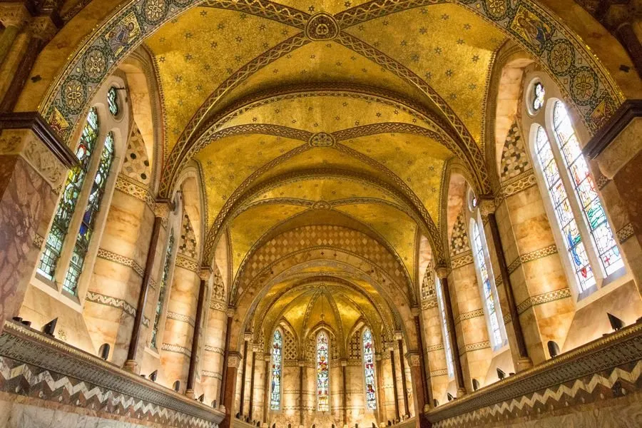 The gold mosaic vaulted ceiling and stained glass windows inside the Fitzrovia Chapel