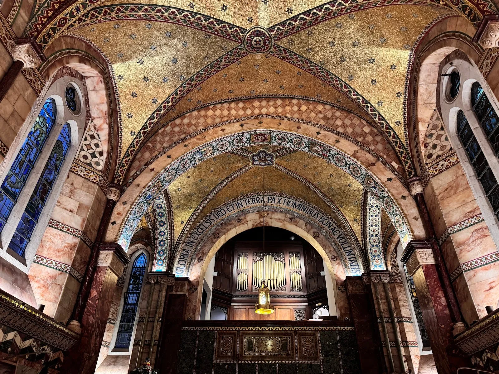 The gold mosaic vaulted ceiling of the Fitzrovia Chapel, with a starred pattern above a Latin inscription