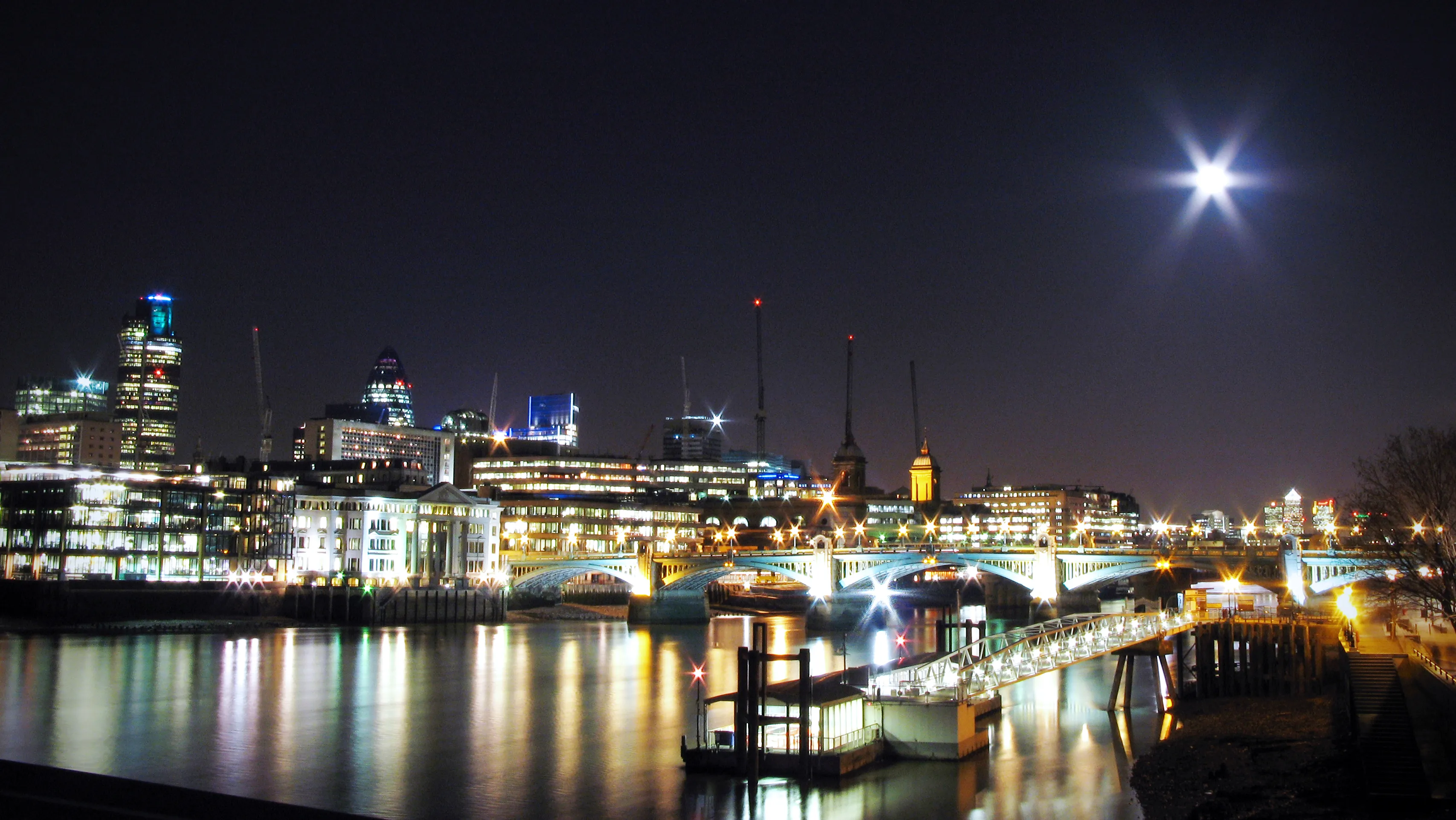 The illuminated City of London skyline reflected in the Thames at night