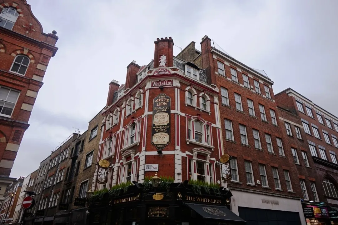The red-brick corner front of the White Lion pub by day, with a Floral Street WC2 sign on its wall