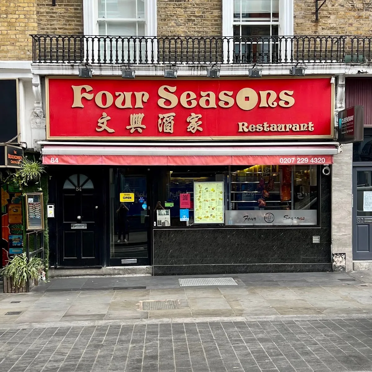 Four Seasons' red shopfront at 84 Queensway, with gold lettering and a menu board in the window