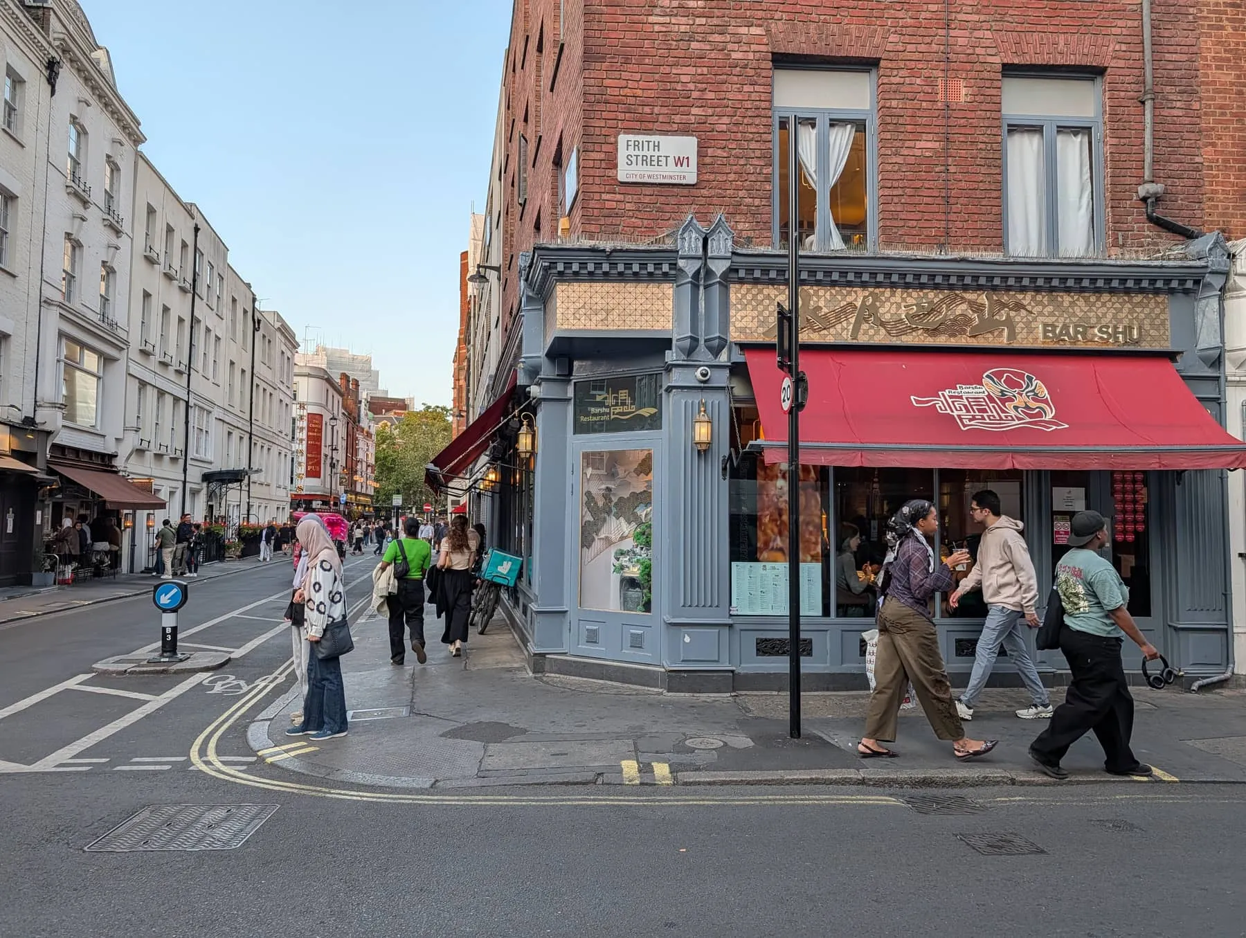 The corner of Frith Street in Soho, with the street sign above a red-awninged restaurant frontage