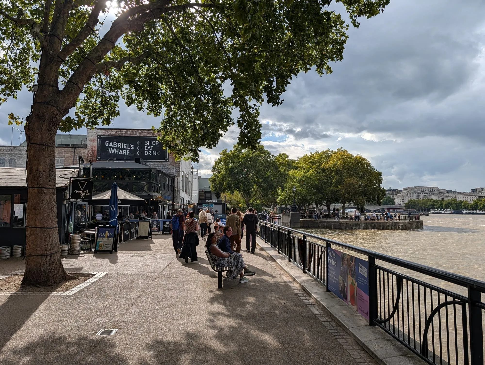 The riverside walk at Gabriel's Wharf, a signed run of small shops and food units under plane trees