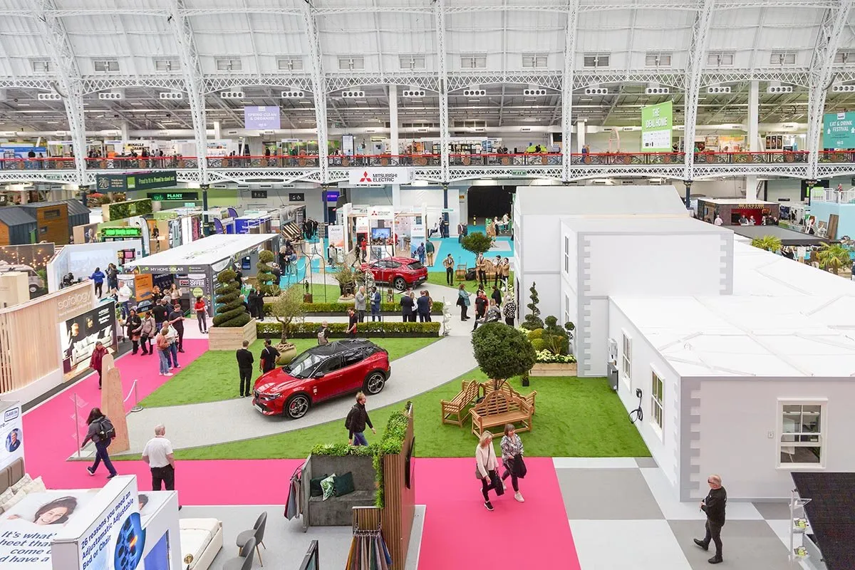 An aerial view of the Ideal Home Show floor at Olympia, garden displays and a car on show beneath banners for The Ideal Home and the Eat & Drink Festival