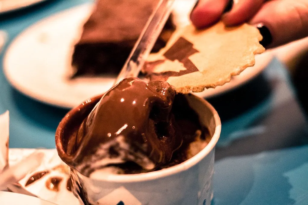 A tub of chocolate gelato with a wafer and a brownie