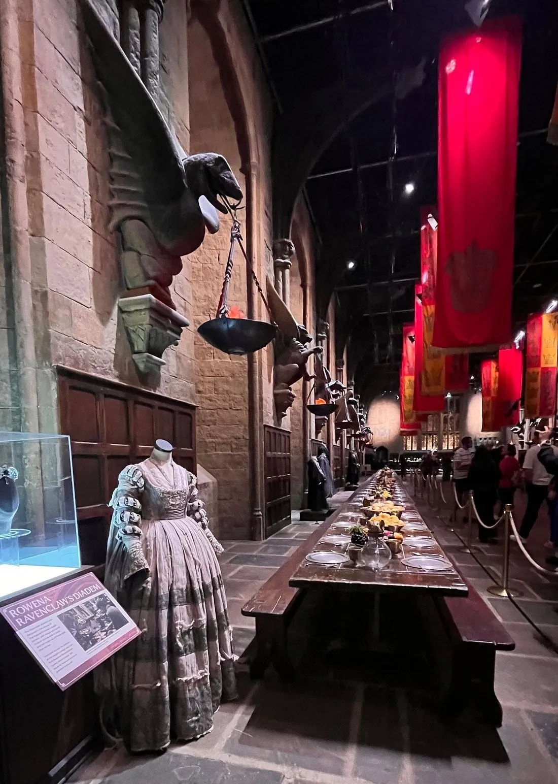 The Great Hall set with its long tables laid for a feast, house banners hanging above and costumes on either side