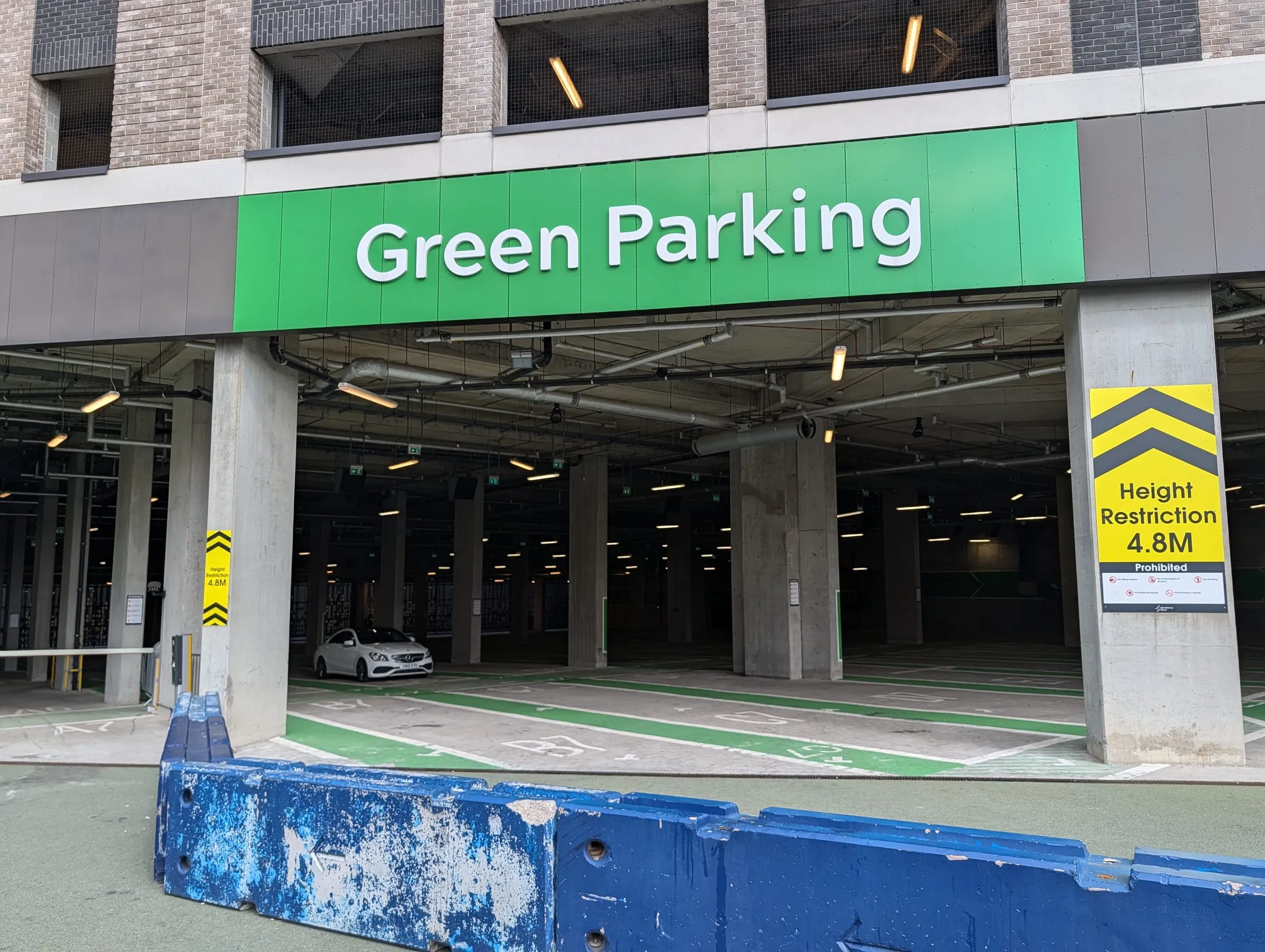 The entrance to Green Parking at Wembley Park, a green sign over the mouth of a multi-storey car park and a yellow 4.8m height restriction sign