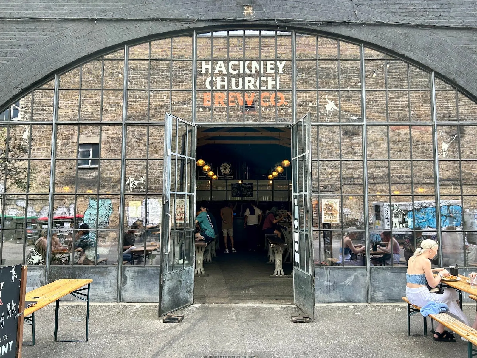 The arched brick frontage of Hackney Church Brew Co. under the railway arches at Bohemia Place, with its name painted above the open doors