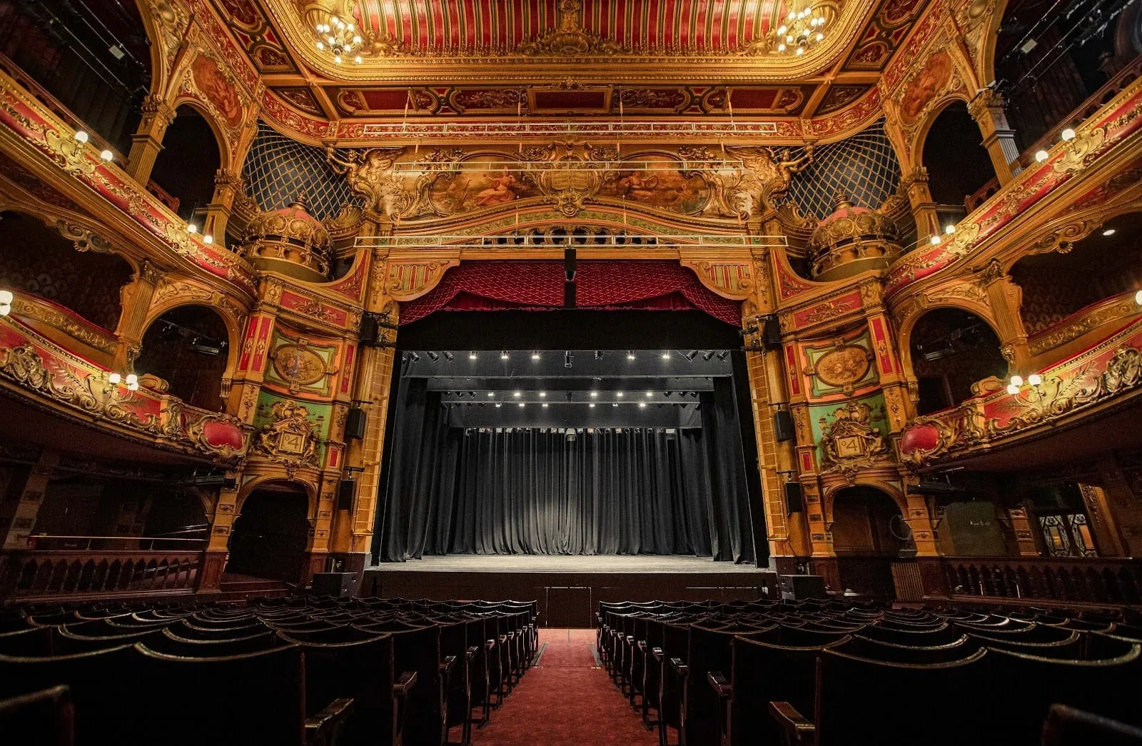 The Hackney Empire's auditorium from the stalls, with gilded and painted boxes either side of the stage and chandeliers in the ceiling