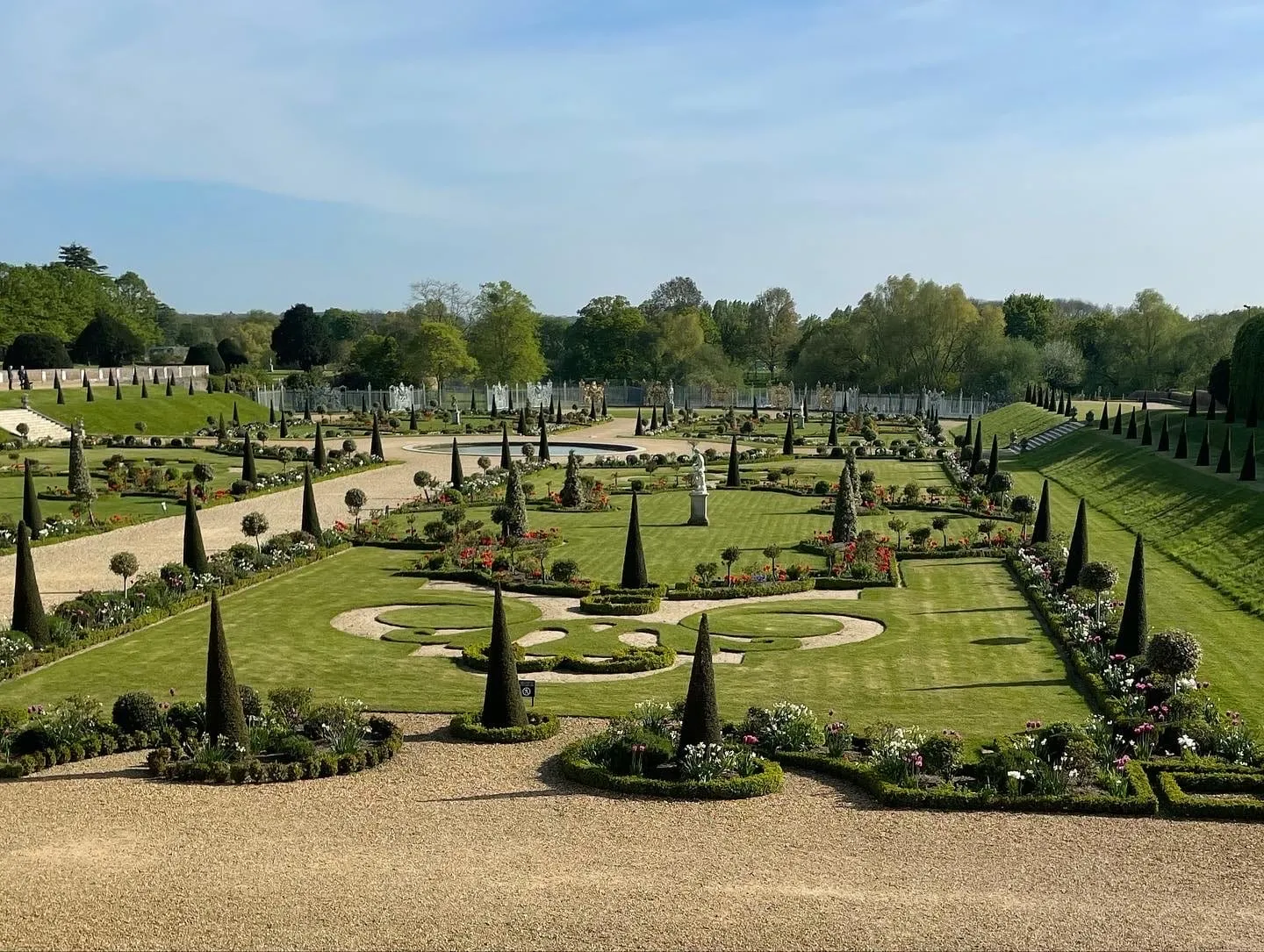 The Privy Garden at Hampton Court Palace, clipped yew obelisks radiating from a circular pond in front of a wrought-iron screen