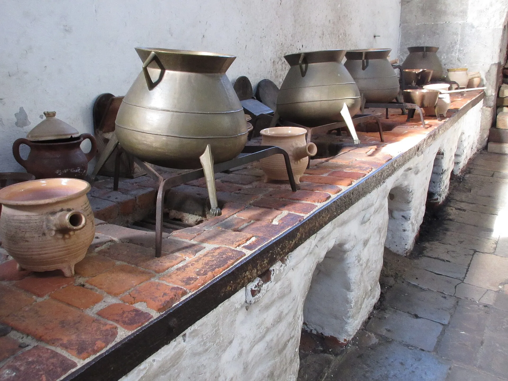 Rows of copper cooking pots set on the brick ranges inside the Tudor Kitchens at Hampton Court Palace