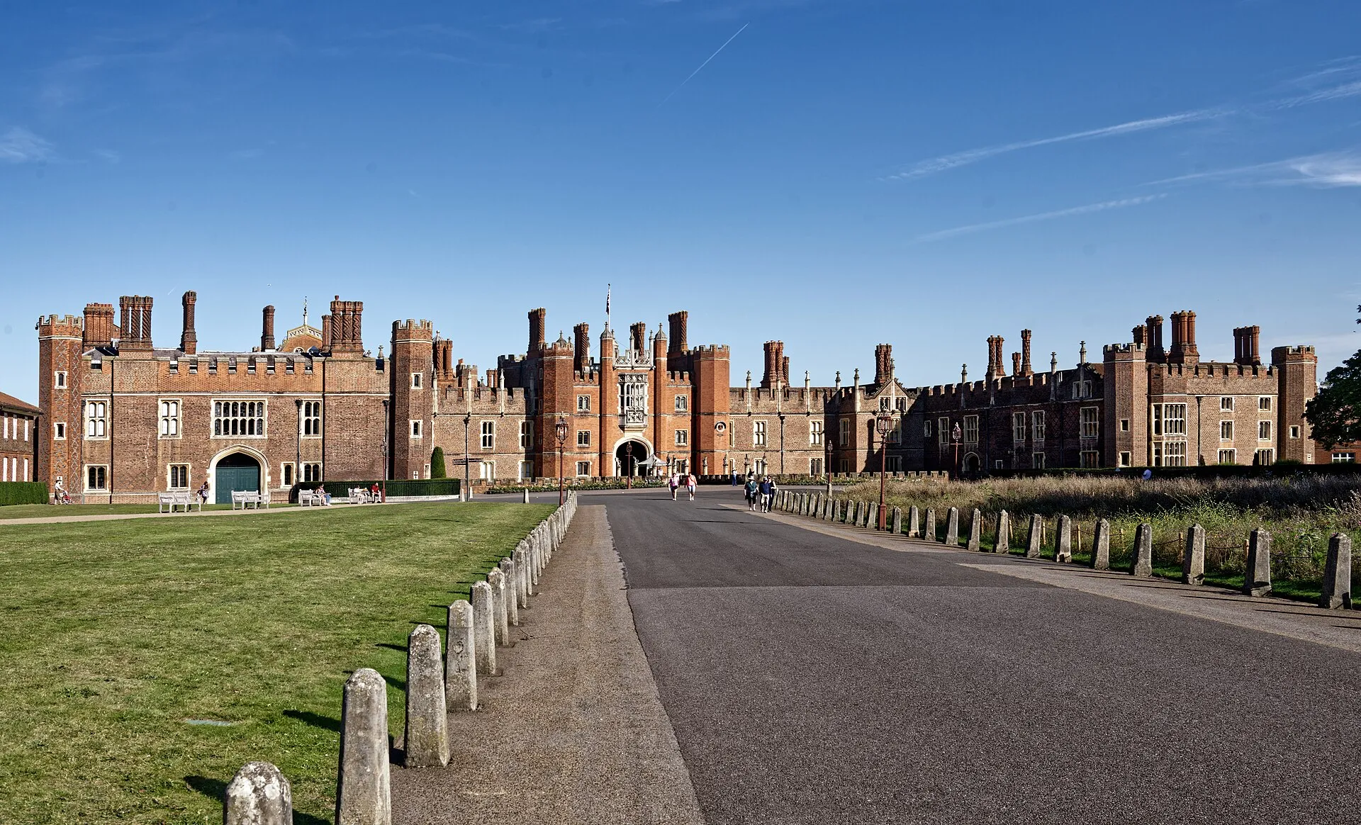 The red-brick Tudor West Front and Great Gatehouse of Hampton Court Palace with its twisted chimneys under a clear blue sky
