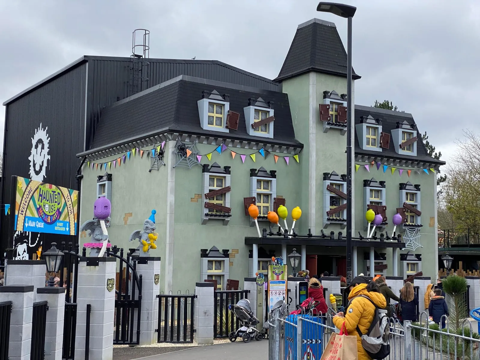 The Haunted House Monster Party building at LEGOLAND, a grey-green mansion with boarded windows, bunting and LEGO monster figures by the entrance