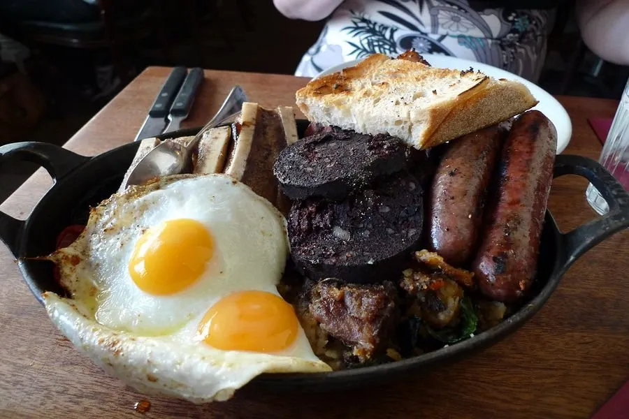 A Hawksmoor breakfast of fried eggs, black pudding, sausages, mushrooms and bone marrow in a cast iron pan