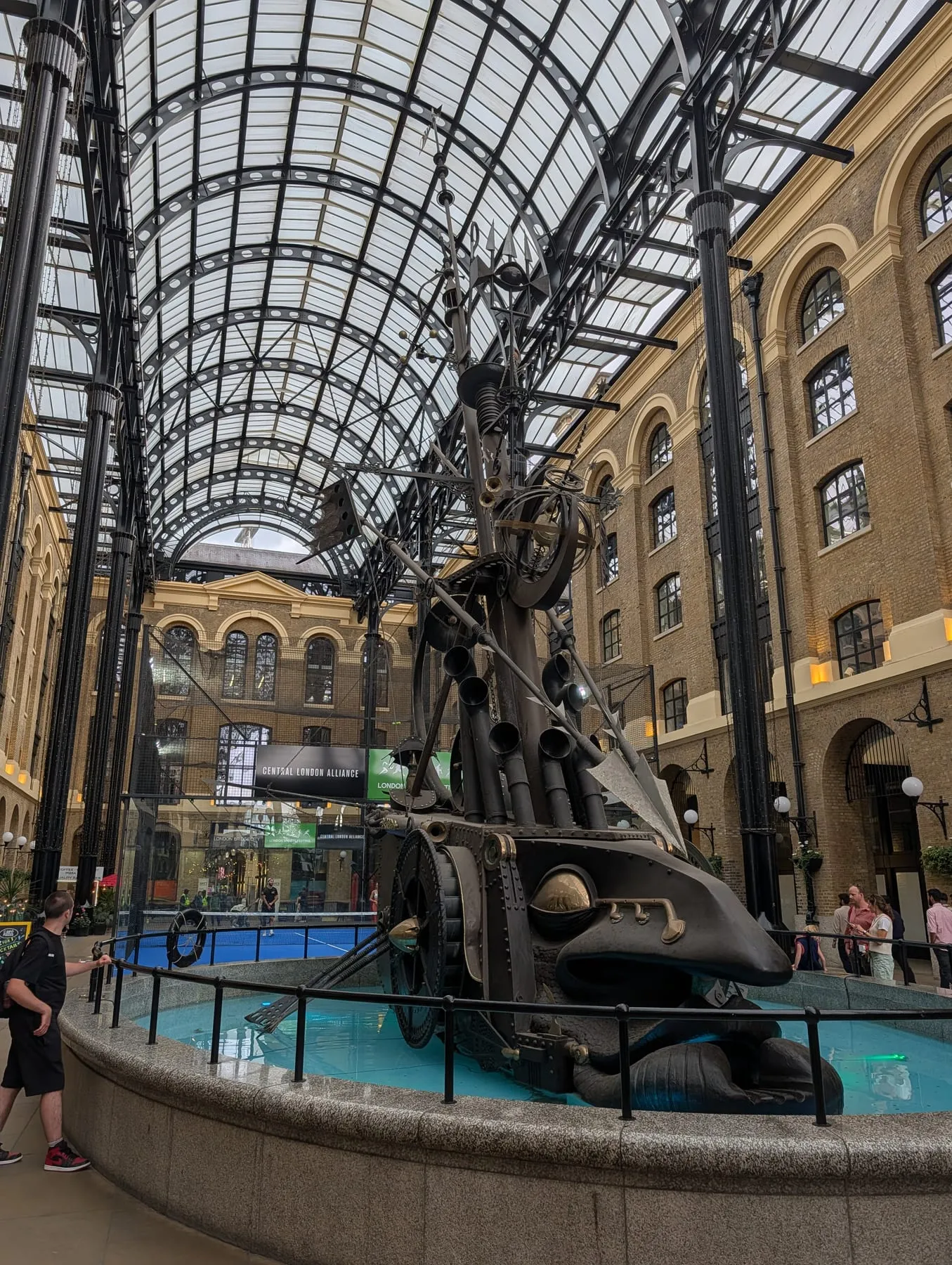 The Navigators, a tall kinetic sculpture of ship parts, under the glass barrel vault of Hay's Galleria