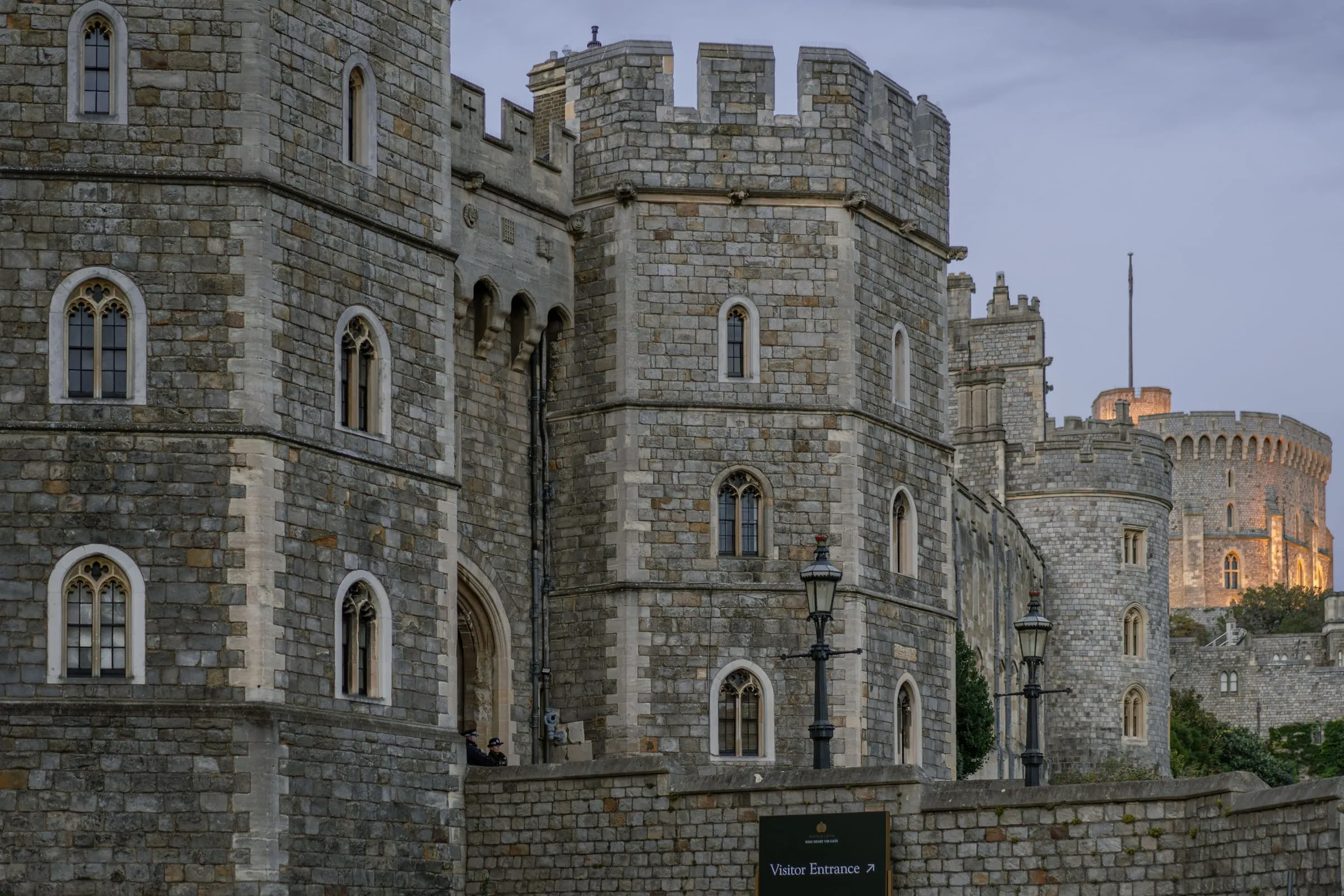 Windsor Castle's Henry VIII Gate and battlements at dusk, lit by street lamps