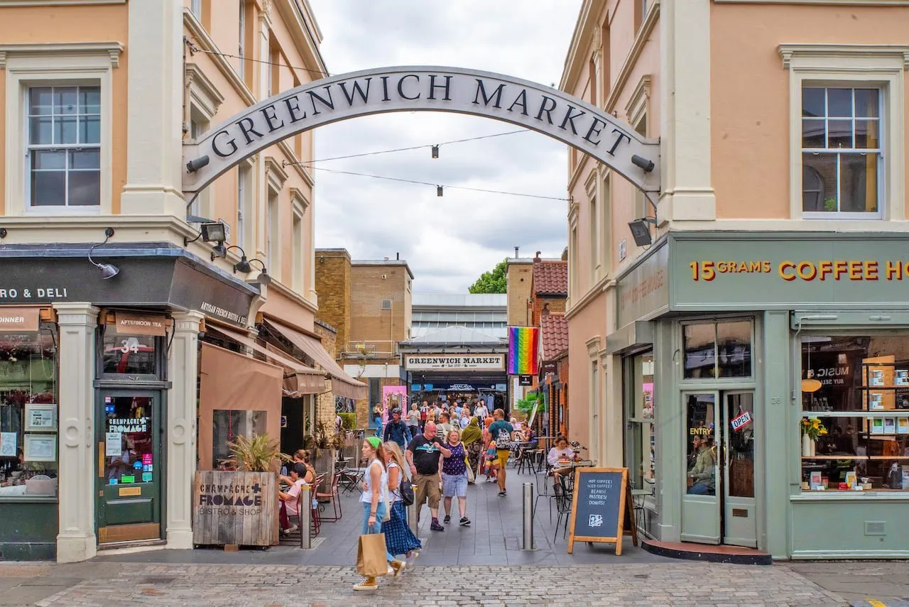 The Greenwich Market arch on Greenwich Market street, with shoppers walking towards the market hall