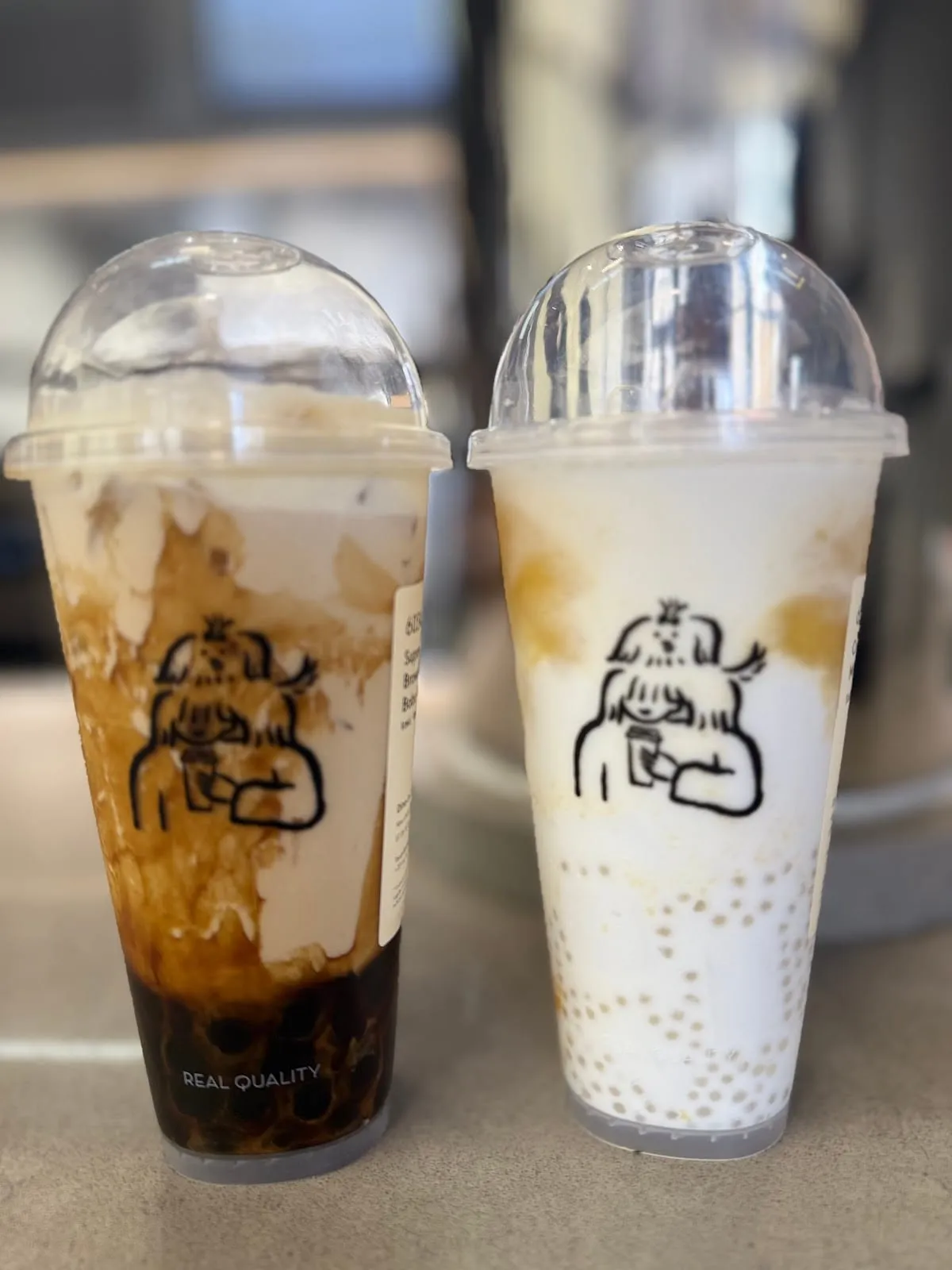 Two HEYTEA cups side by side: brown sugar pearls under milk streaked with syrup, and a milky drink with small sago pearls