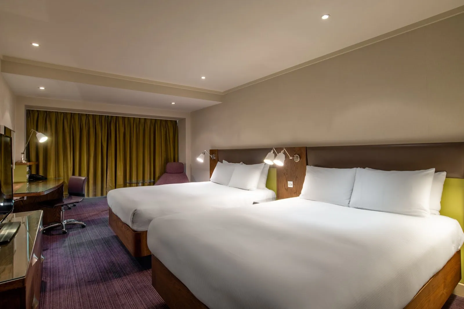 A family bedroom at Hilton London Metropole with two double beds, warm reading lamps and wood headboards