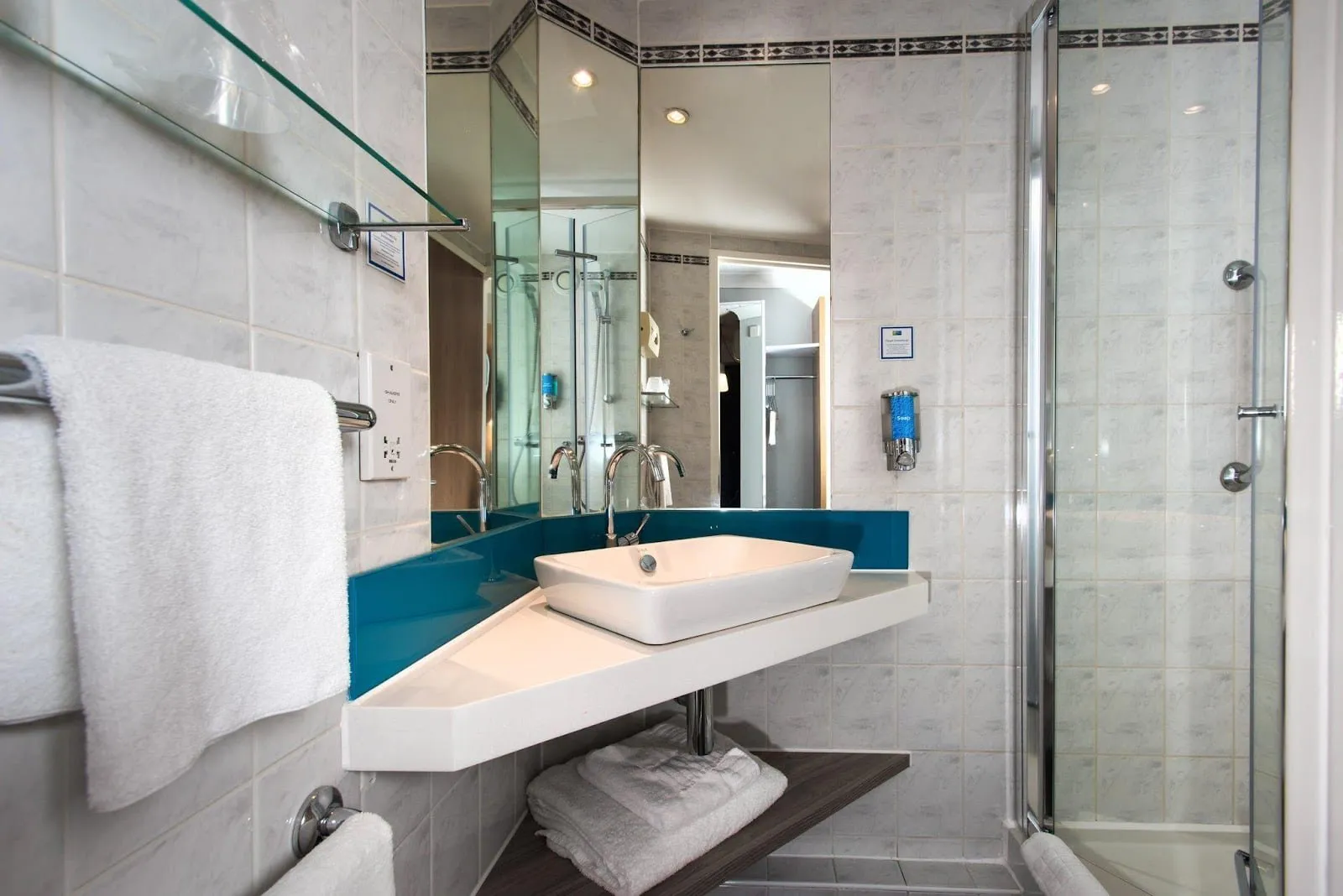 The bathroom at Holiday Inn Express London – Greenwich, with a corner basin and a glass shower